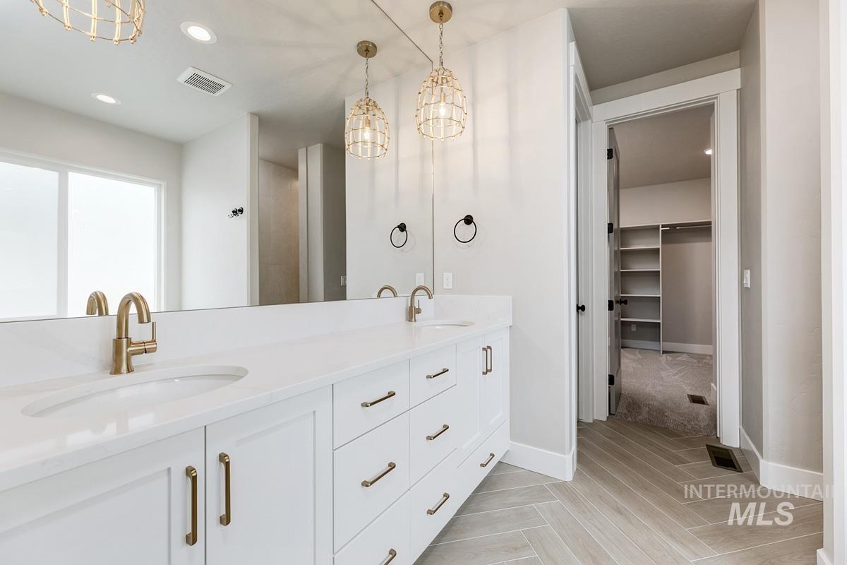 Bathroom featuring recessed lighting, a chandelier, double vanity, a spacious closet, and light wood finished floors