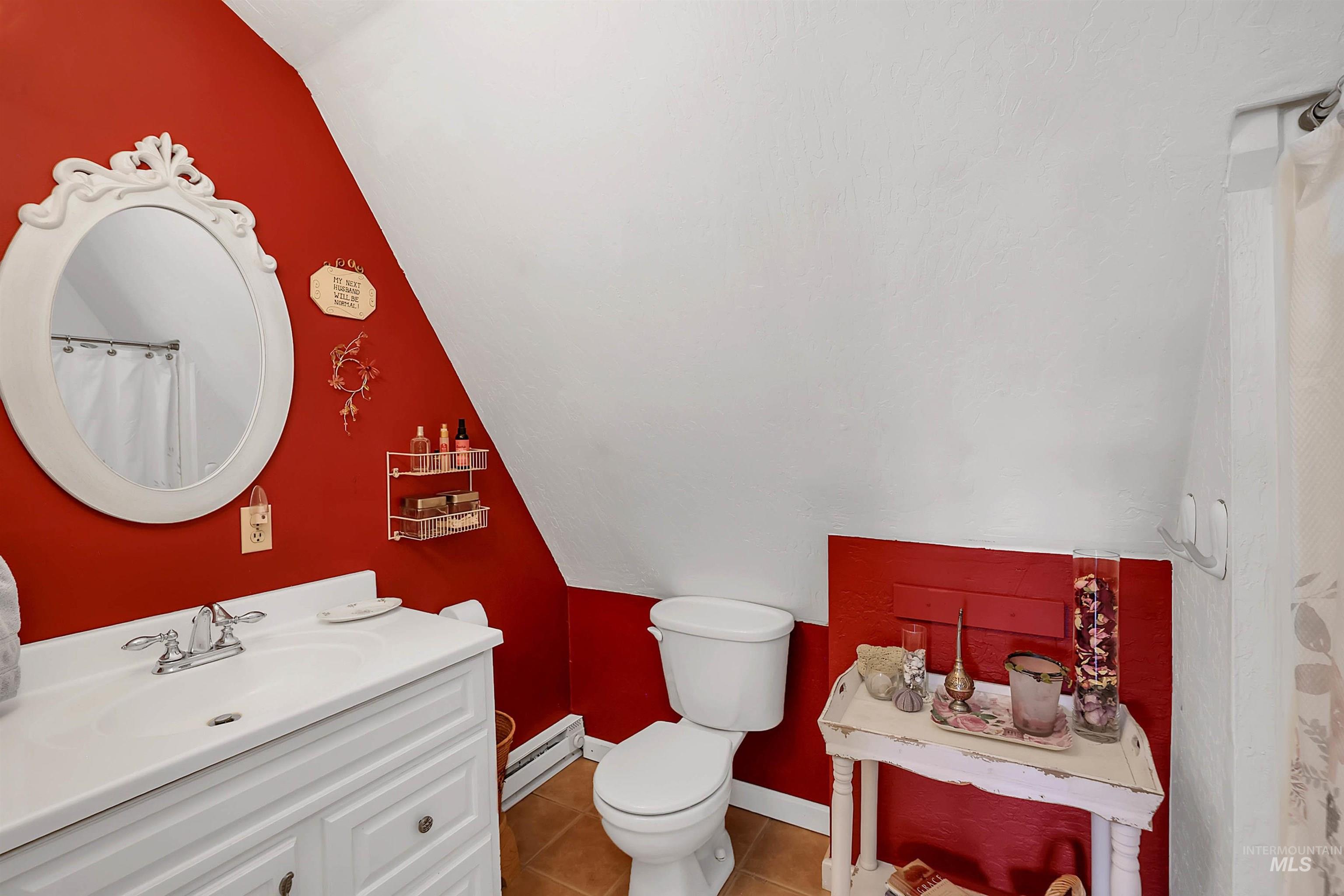 Full bath with lofted ceiling, vanity, tile patterned floors, and a baseboard heating unit