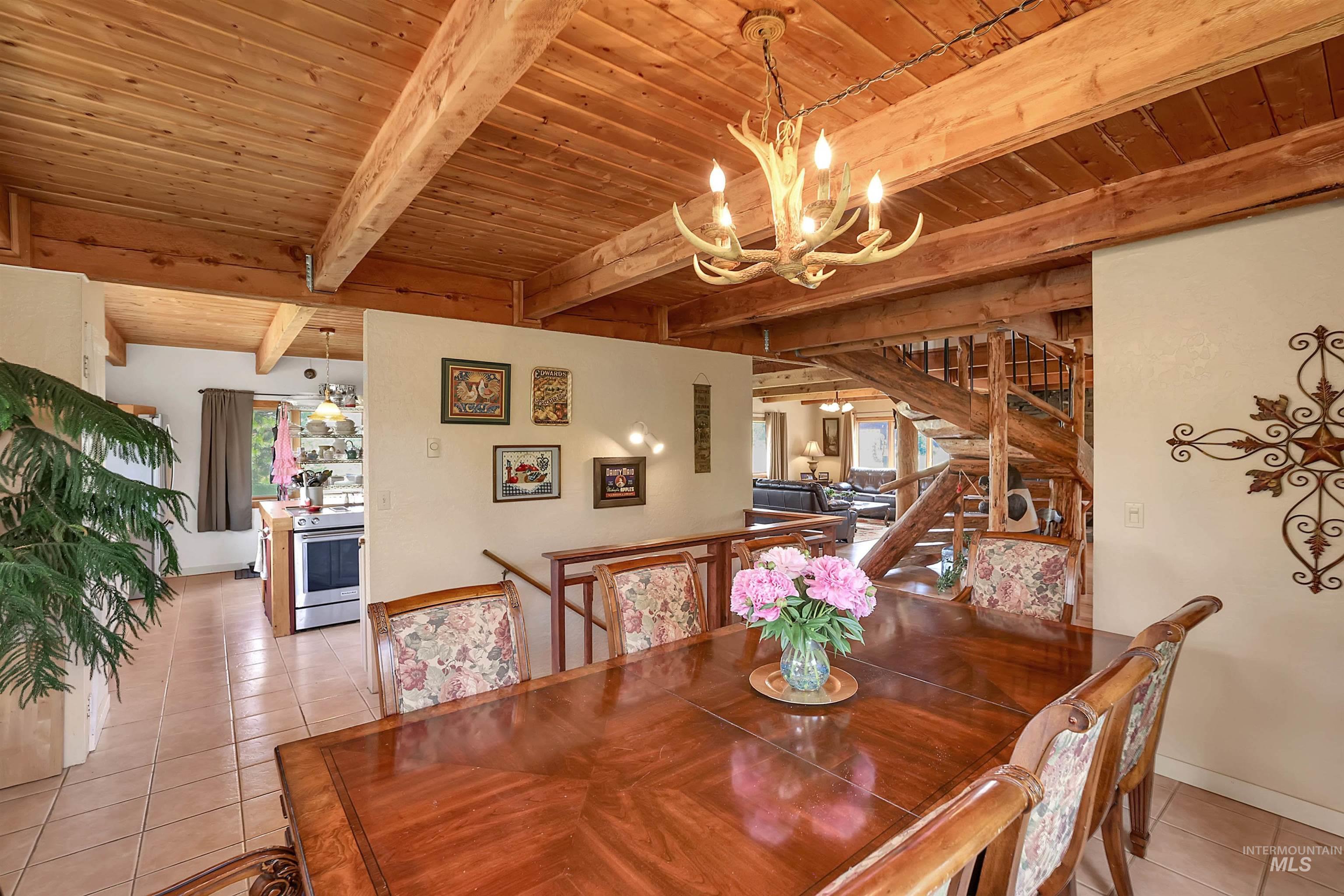 Dining room with light tile patterned floors, a chandelier, and a wooden ceiling with exposed beams