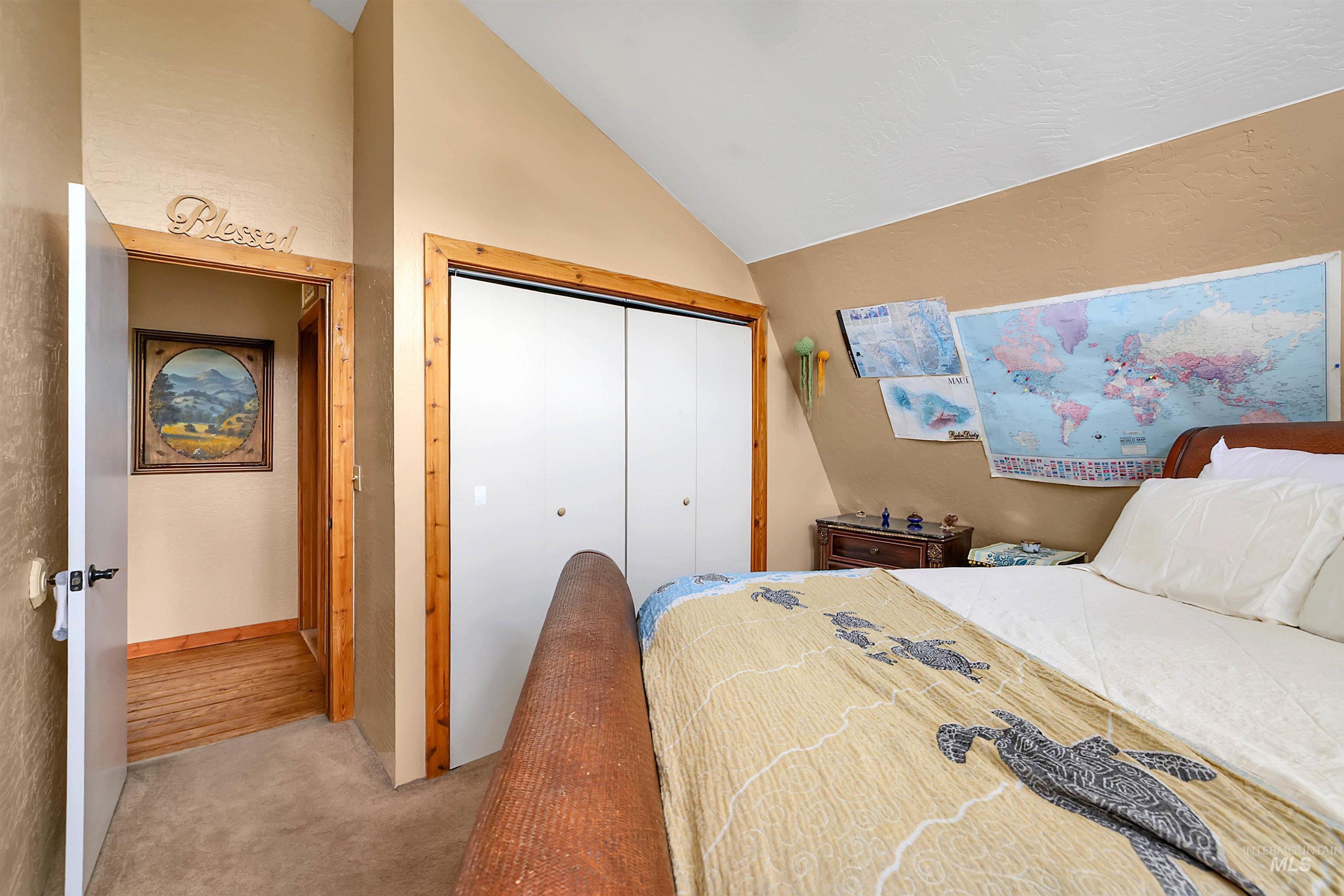 Bedroom featuring light colored carpet, lofted ceiling, and a closet