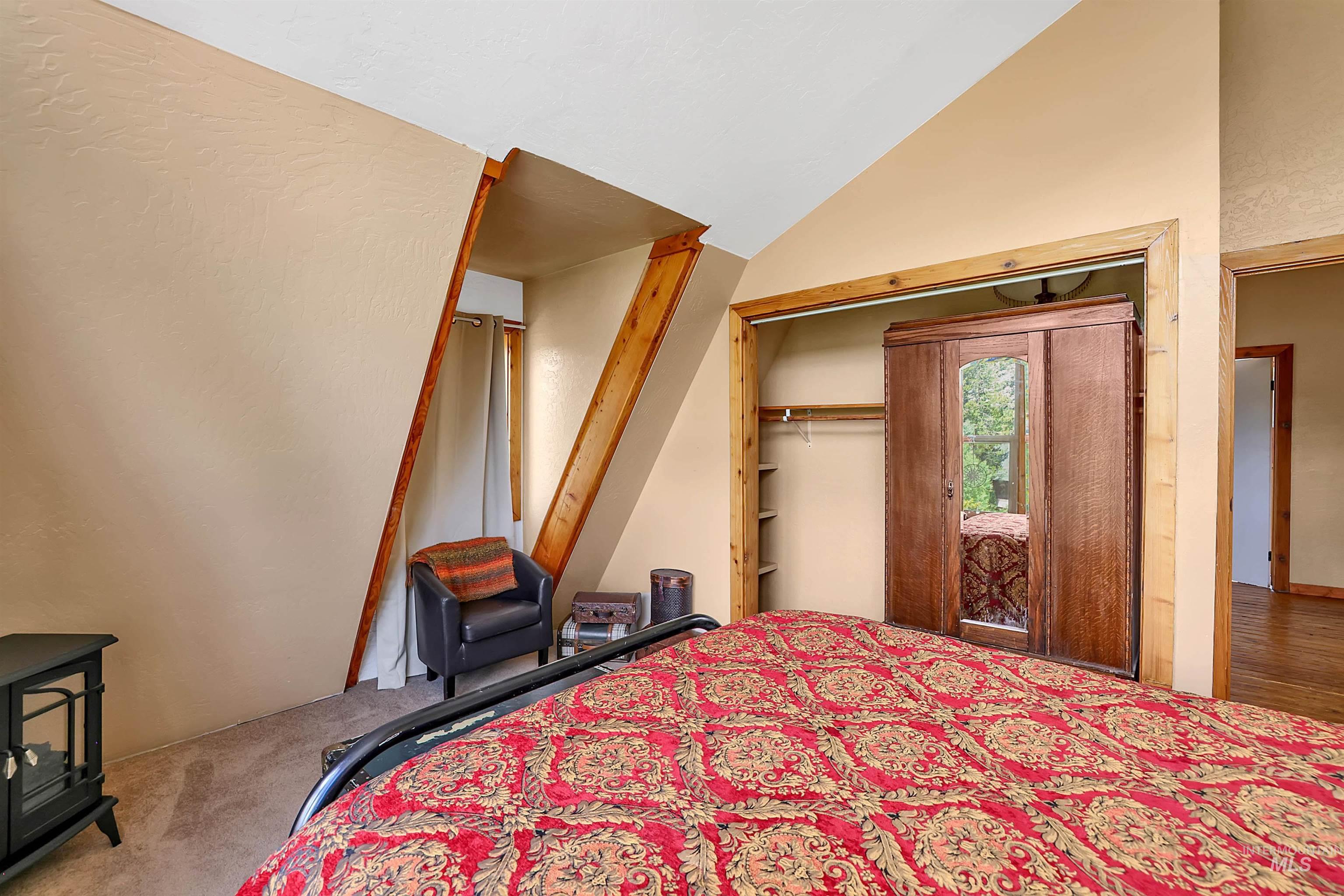 Bedroom with a wood stove, carpet, high vaulted ceiling, and a closet