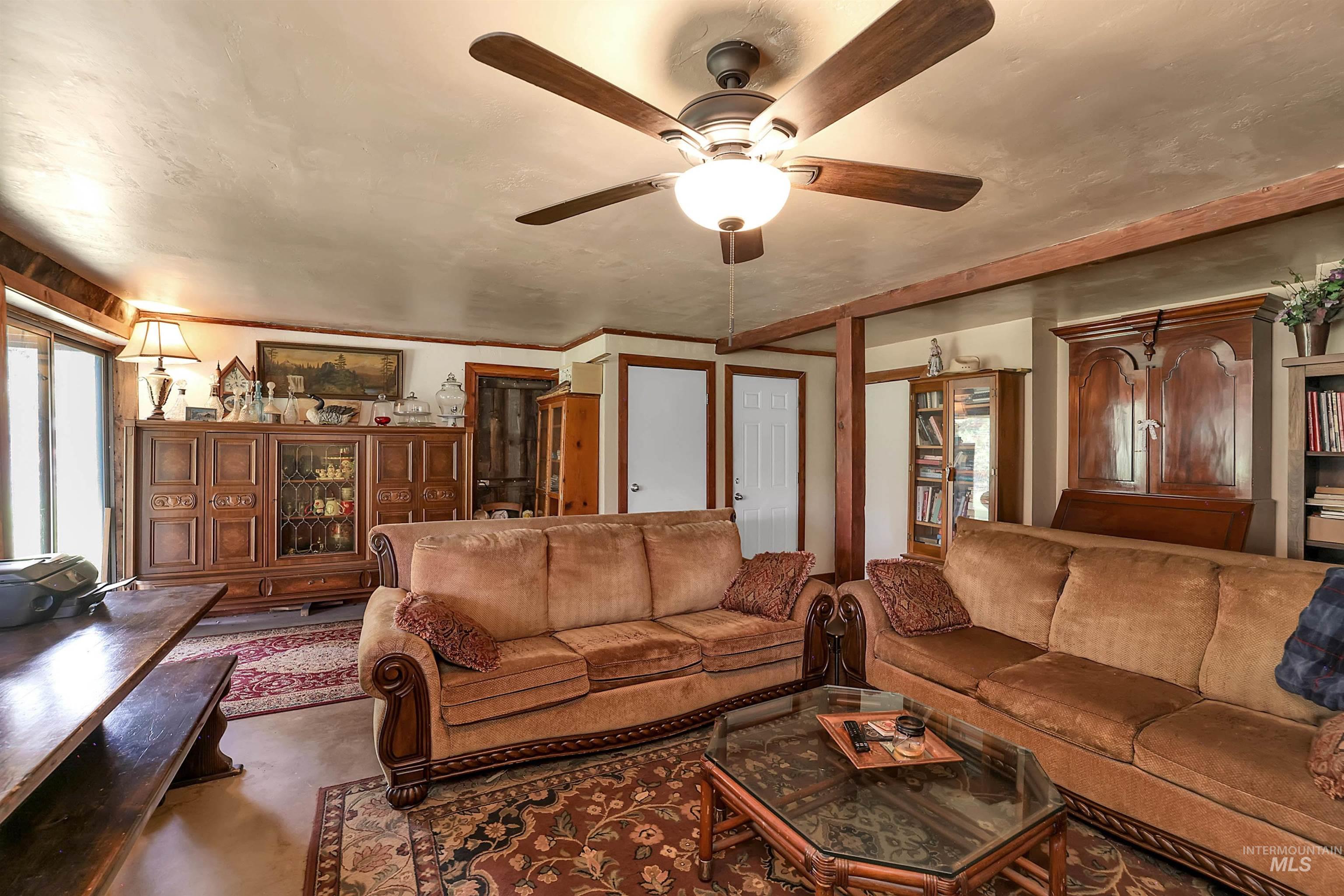 Living area with a ceiling fan and concrete flooring