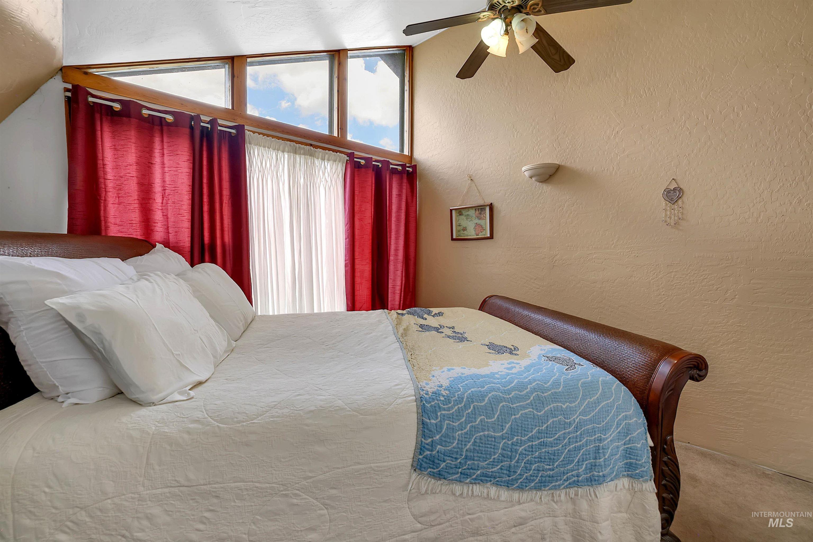 Bedroom featuring a ceiling fan, a textured wall, and carpet floors
