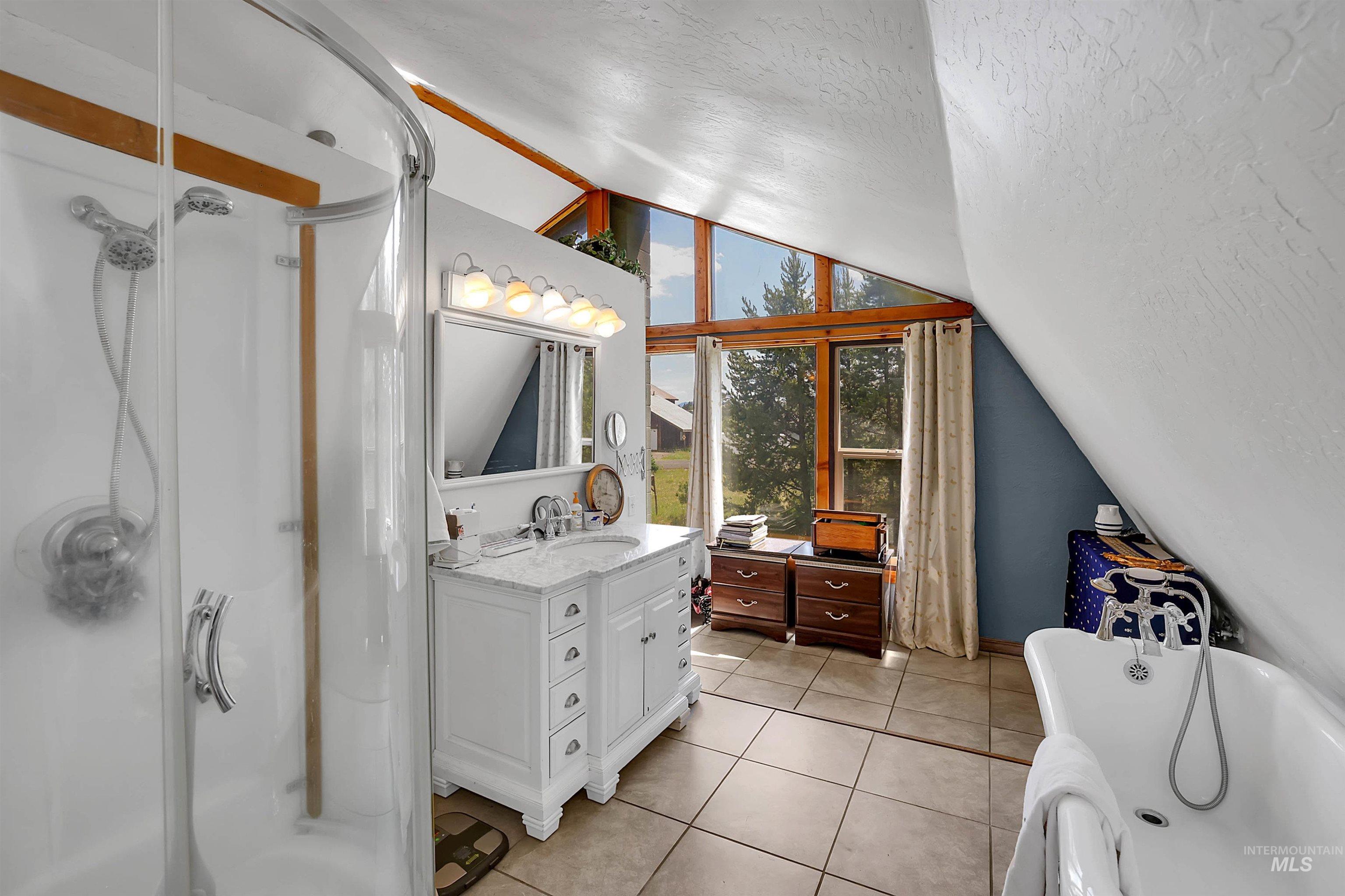 Full bathroom featuring lofted ceiling, vanity, a tub to relax in, a shower stall, and a textured ceiling