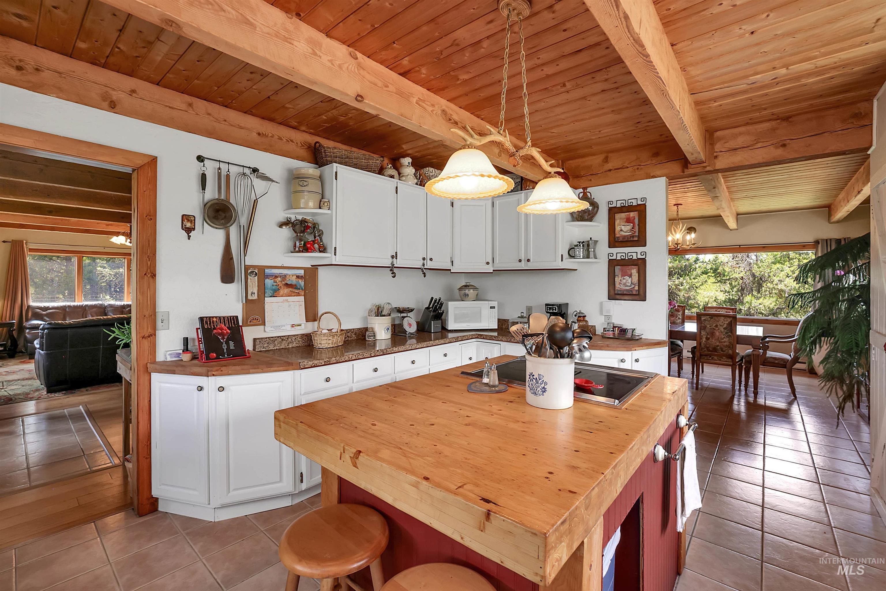 Kitchen with open shelves, butcher block countertops, light tile patterned flooring, a wooden ceiling with exposed beams, and white cabinetry