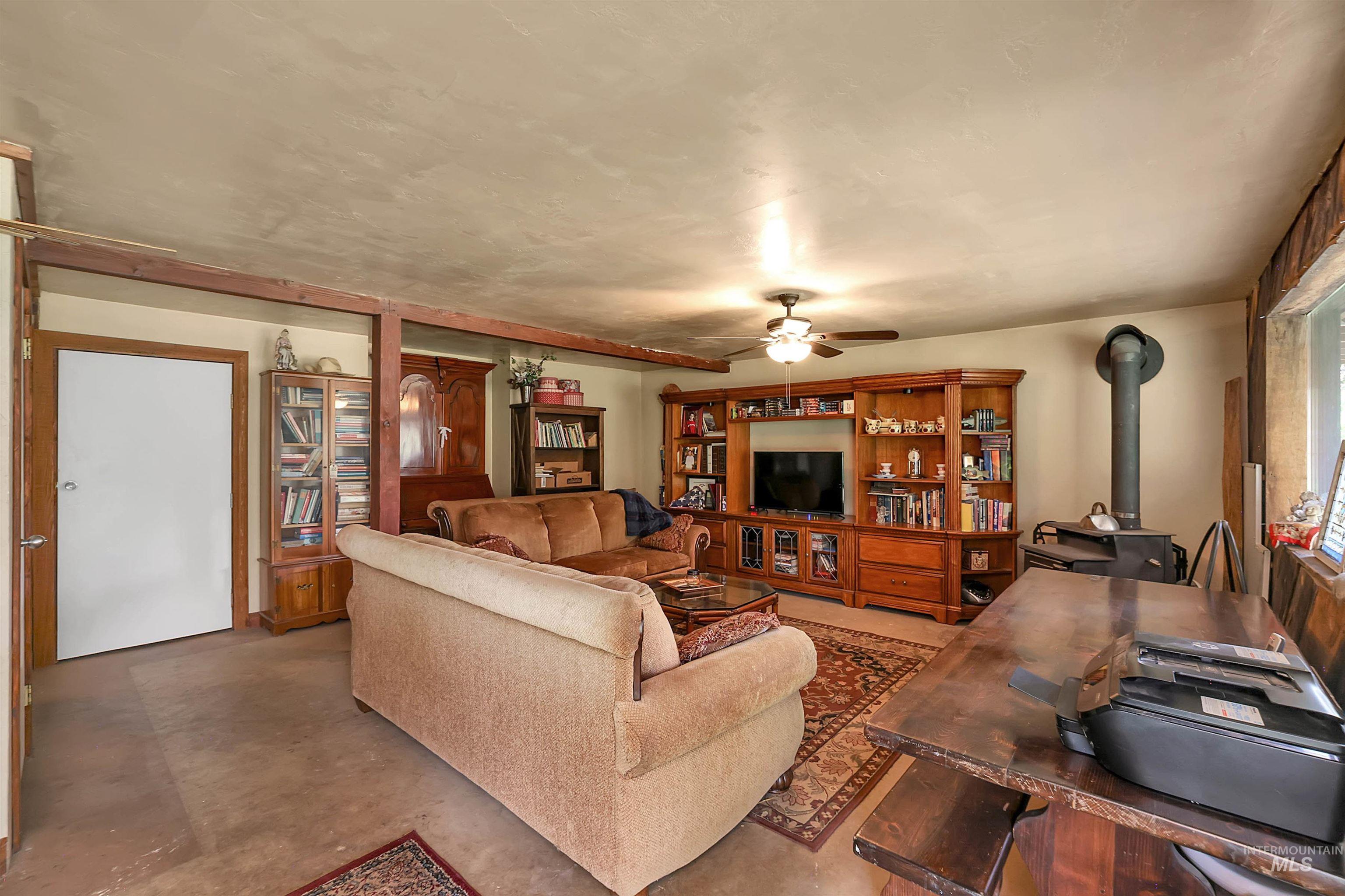 Living area with a wood stove, finished concrete floors, and ceiling fan