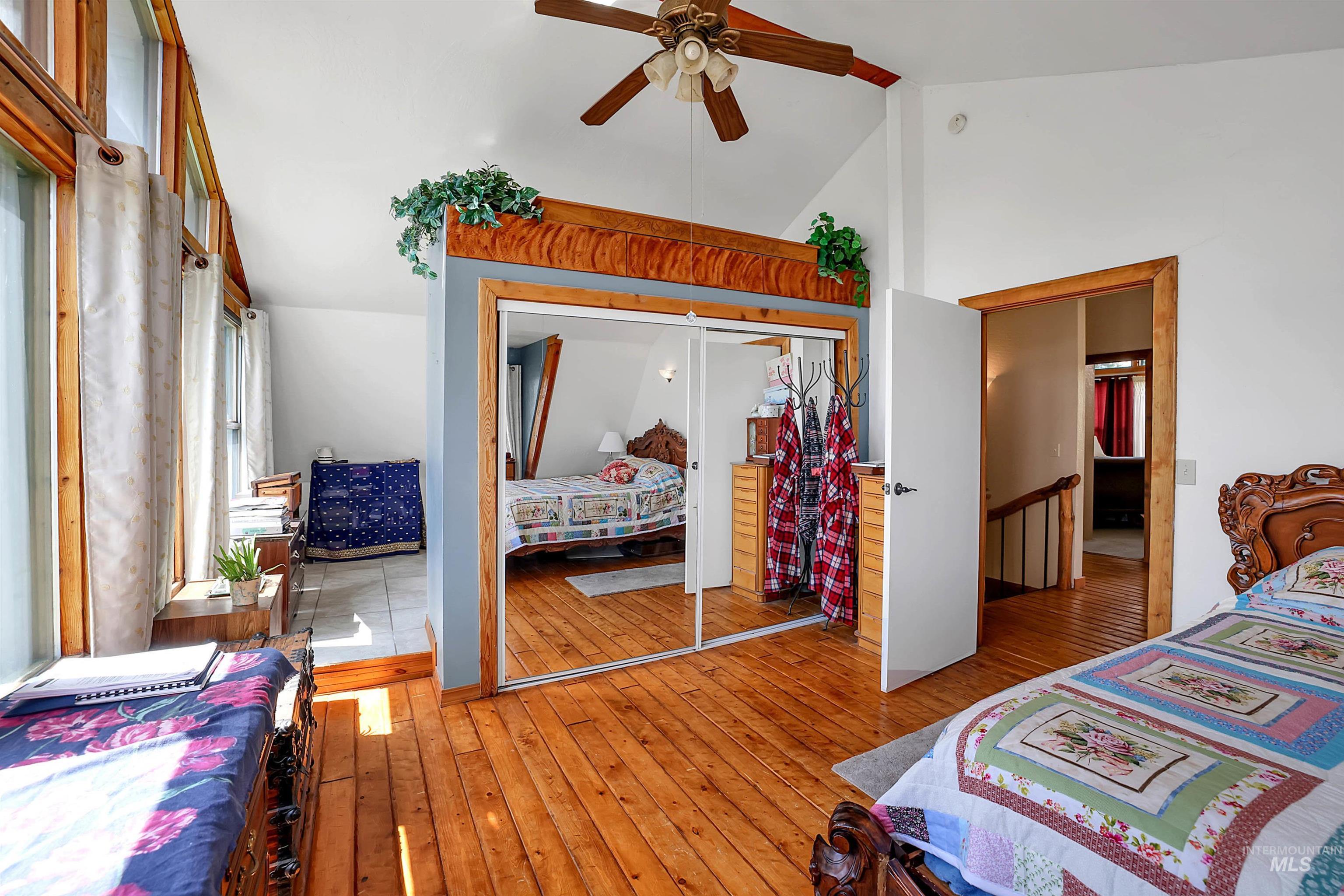 Bedroom with wood-type flooring, a closet, ceiling fan, and high vaulted ceiling