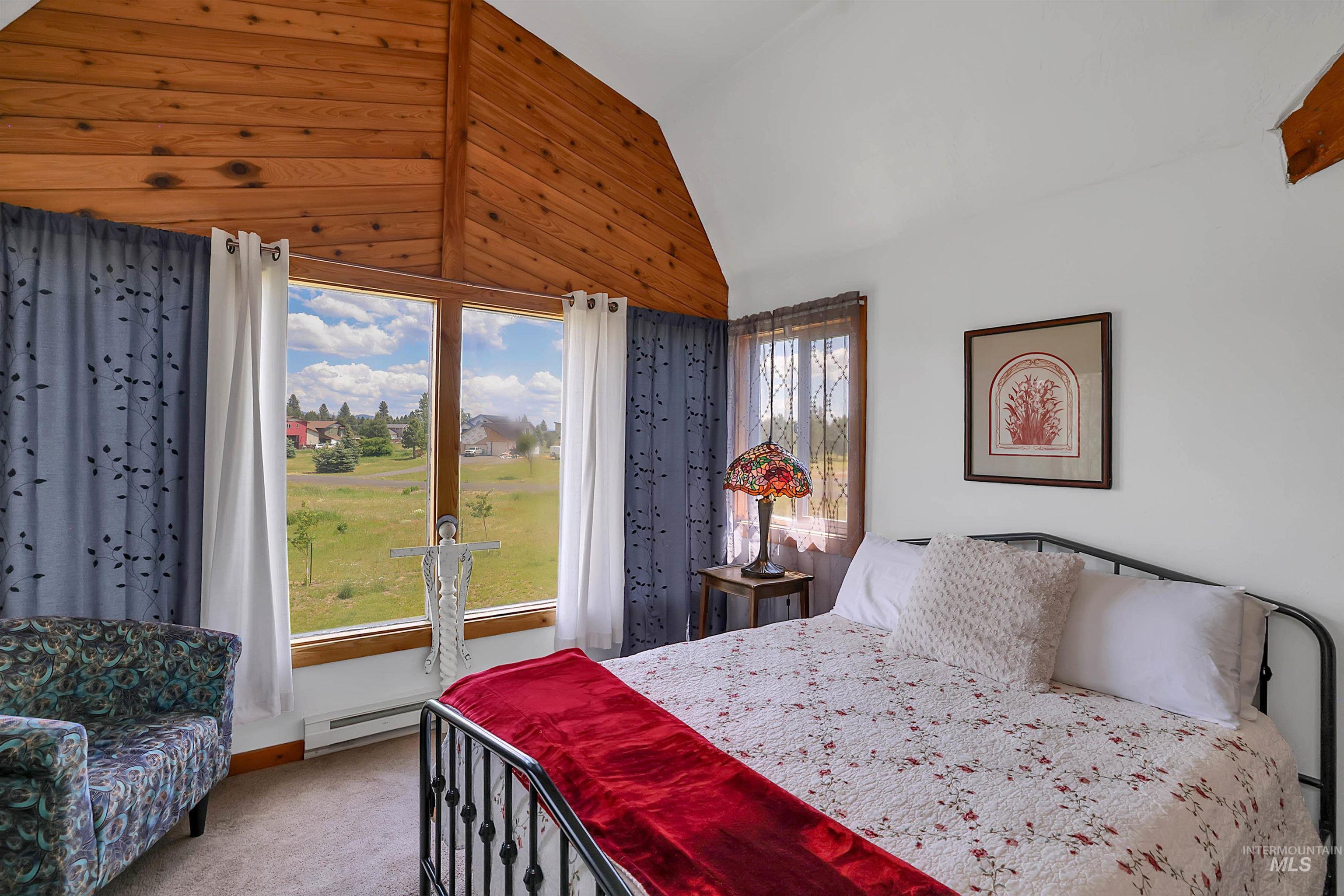Carpeted bedroom featuring a baseboard heating unit and high vaulted ceiling