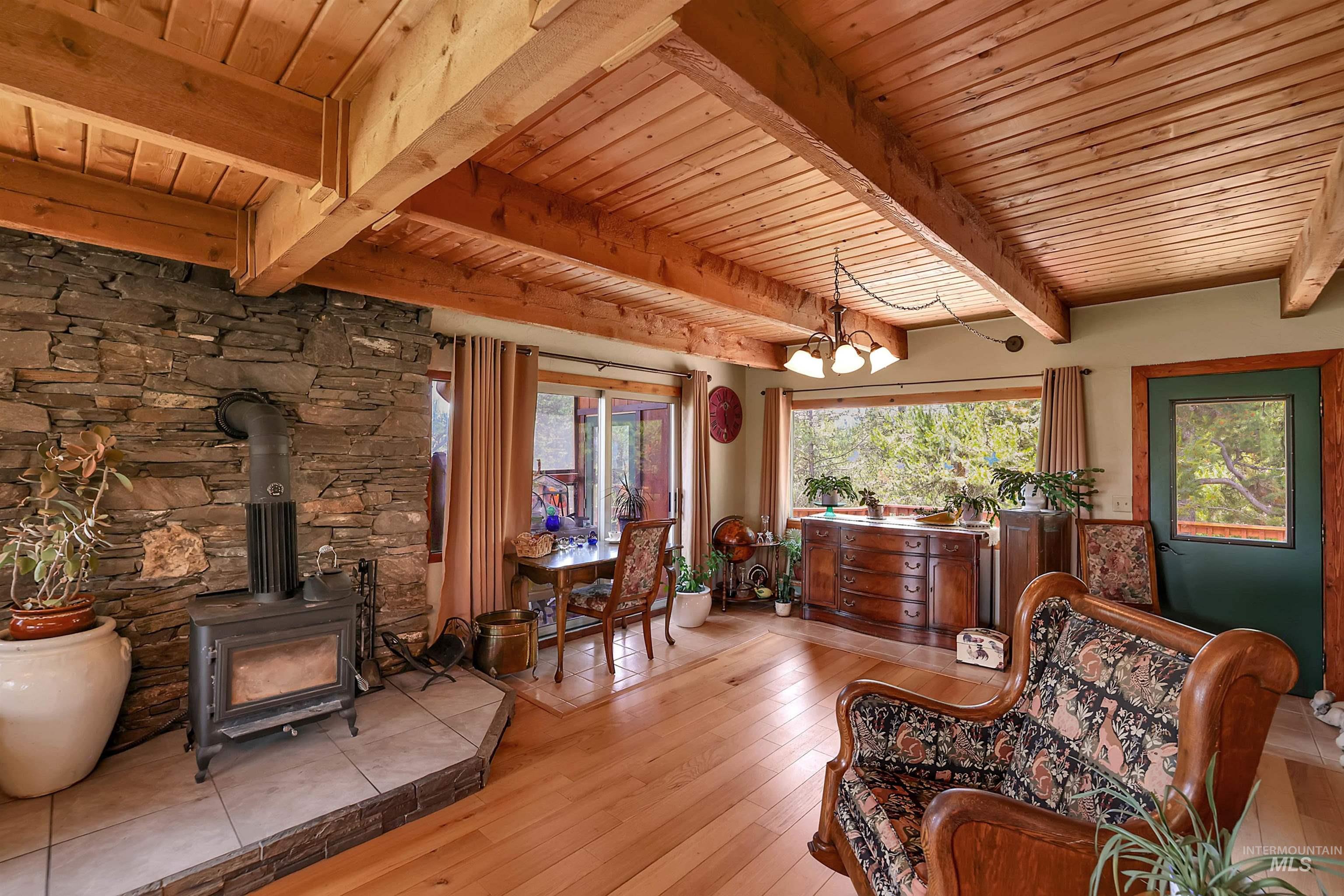 Sitting room featuring a wooden ceiling with exposed beams, a wood stove, light wood-type flooring, and a chandelier