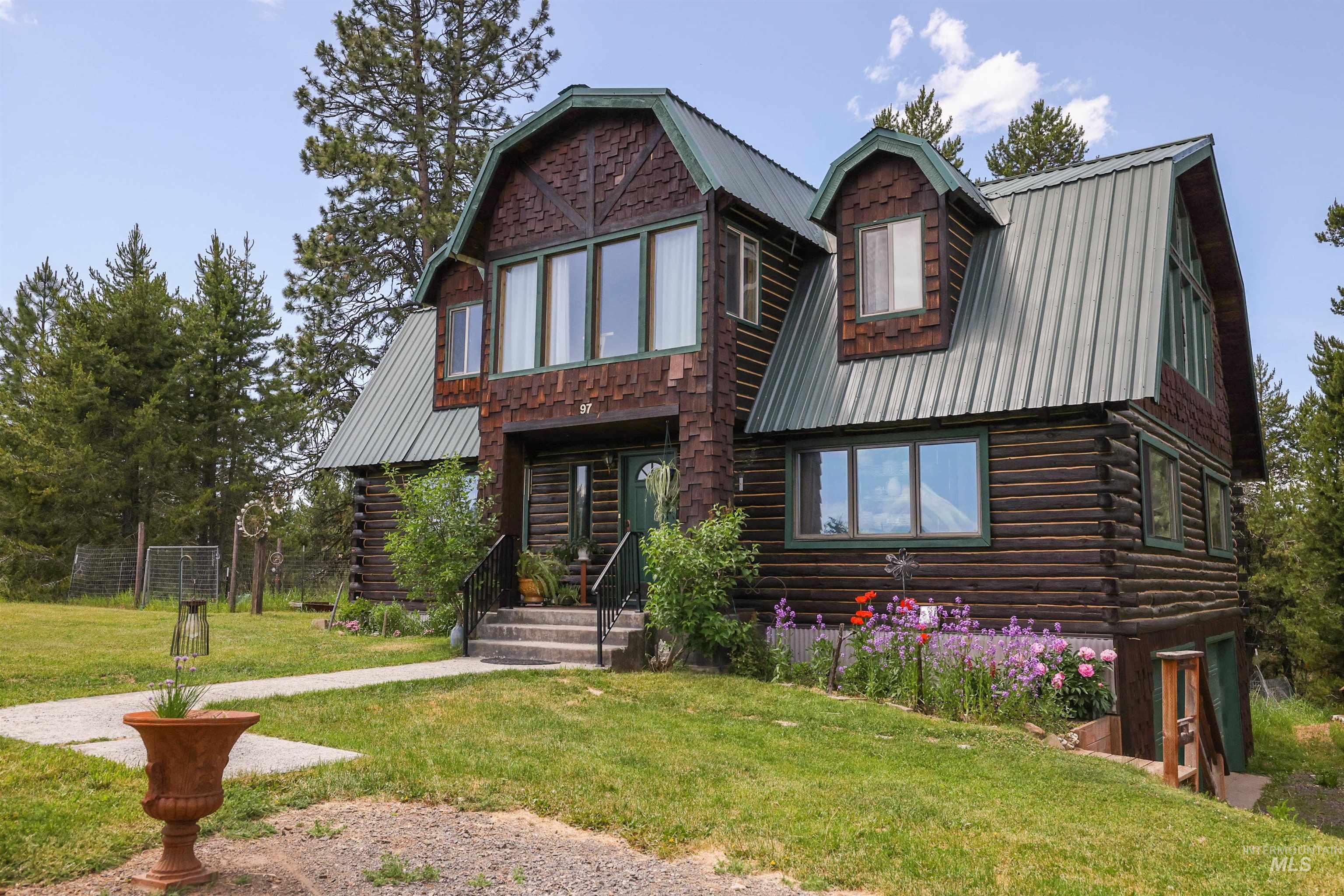 Log-style house with a gambrel roof, log siding, a metal roof, and a front yard