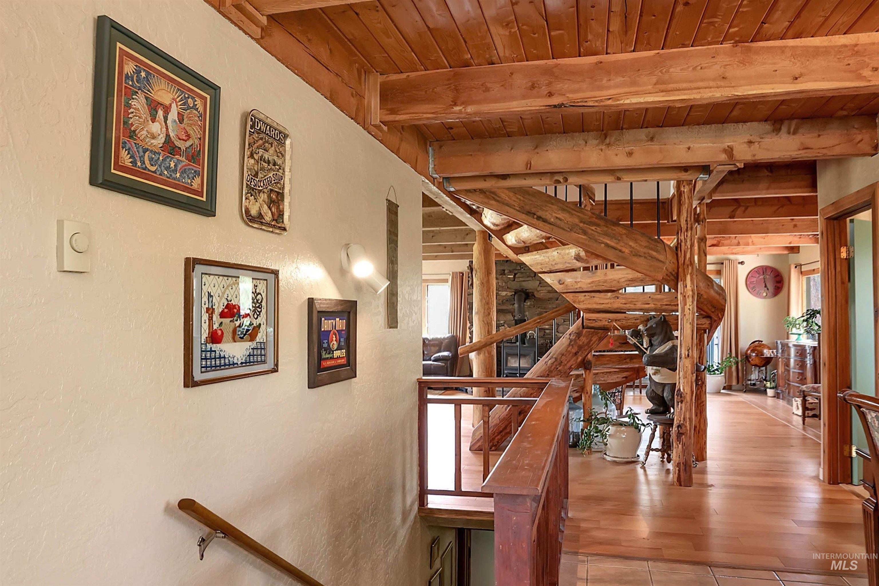 Staircase featuring a wood ceiling with exposed beams, a textured wall, and wood finished floors