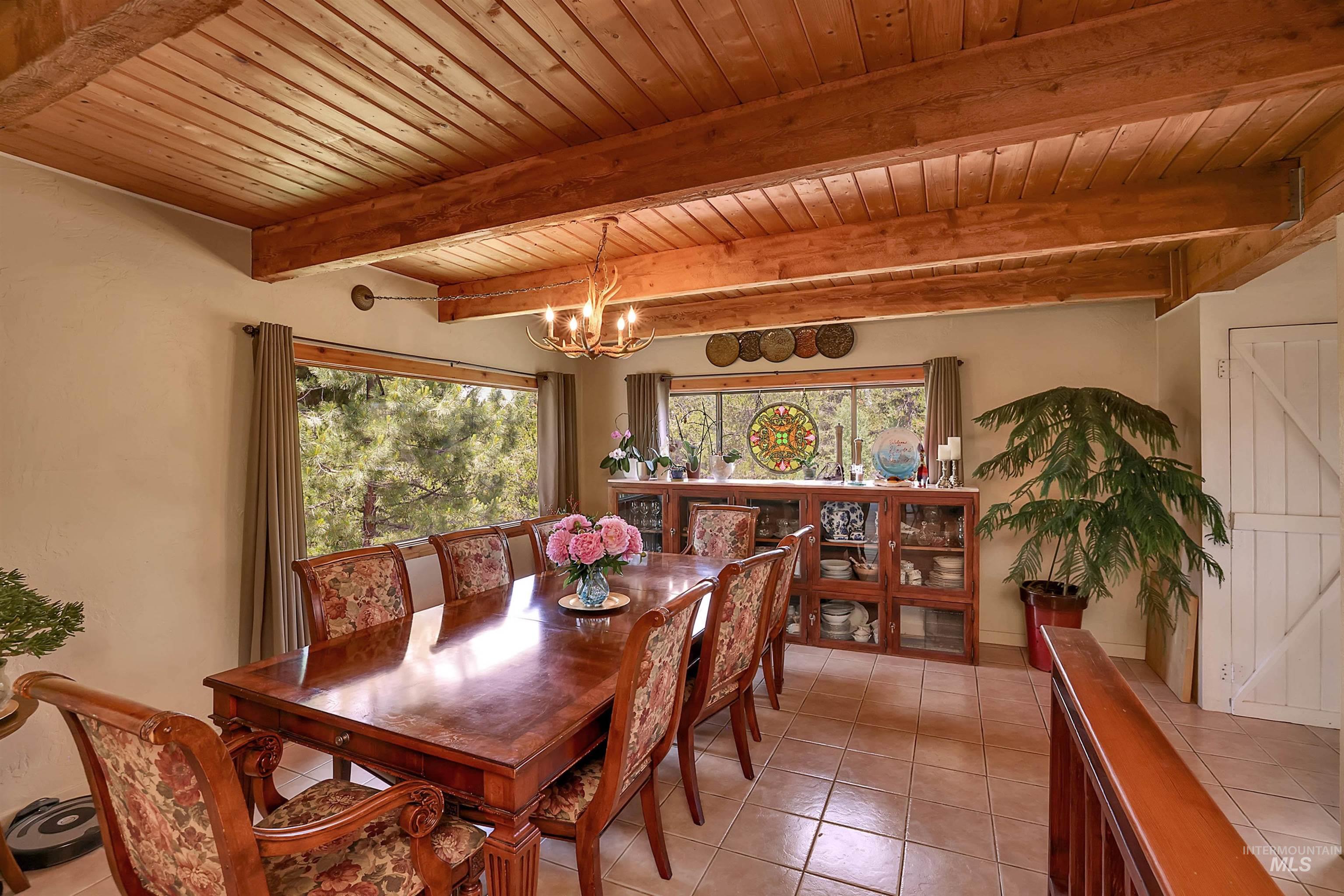 Dining room featuring a chandelier, a wood ceiling with exposed beams, and light tile patterned flooring