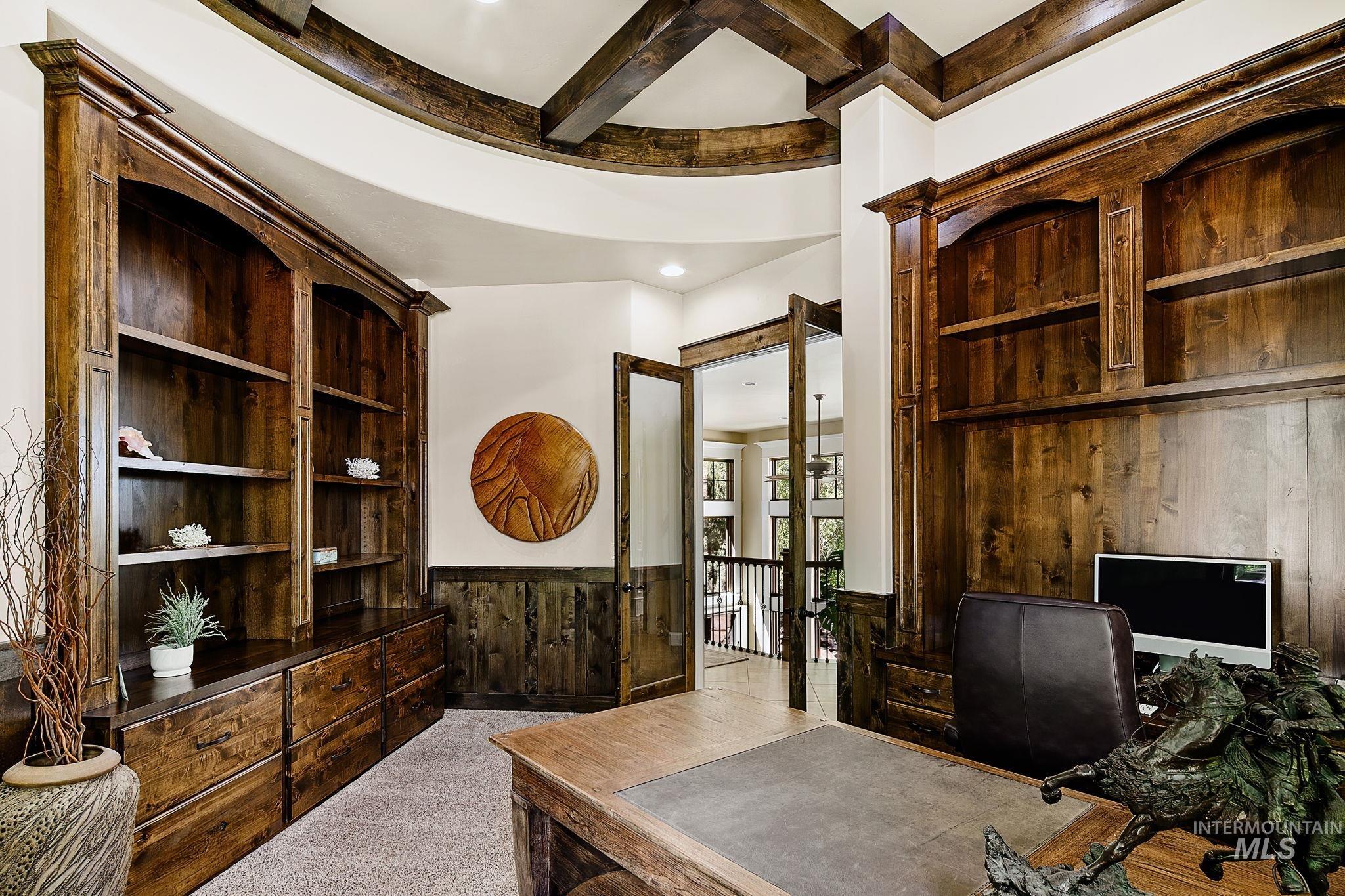 Custom executive office with floor-to-ceiling built-ins, rich wood finishes, and a striking beam-accented ceiling