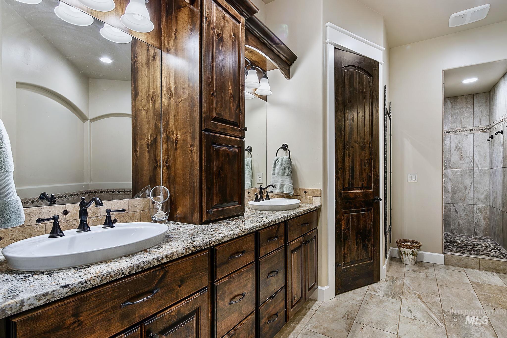 Spa-inspired primary bathroom featuring dual vanities, rich custom cabinetry