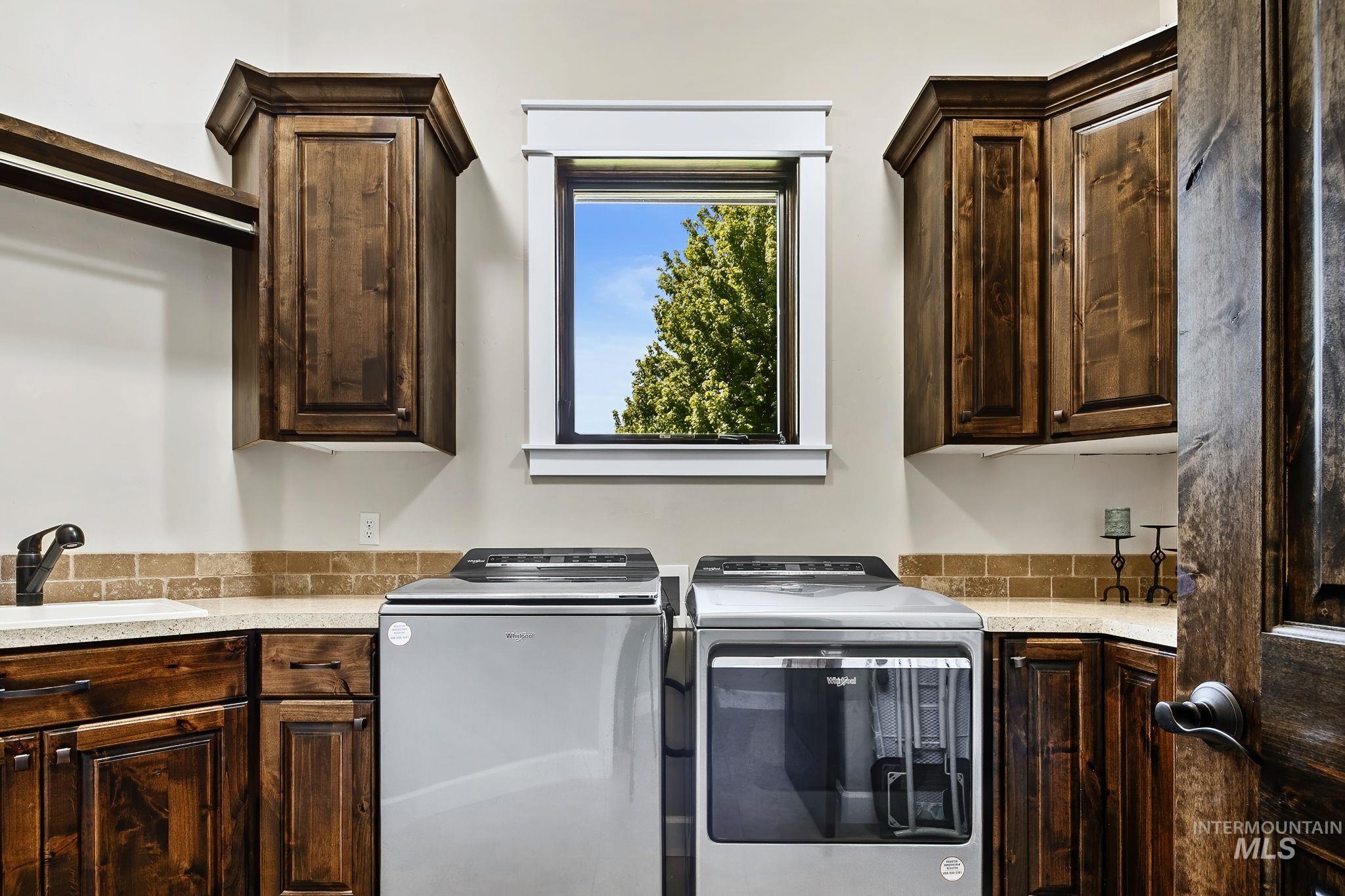 Spacious laundry room featuring extensive cabinetry and countertop workspace, plus a convenient utility sink for added functionality