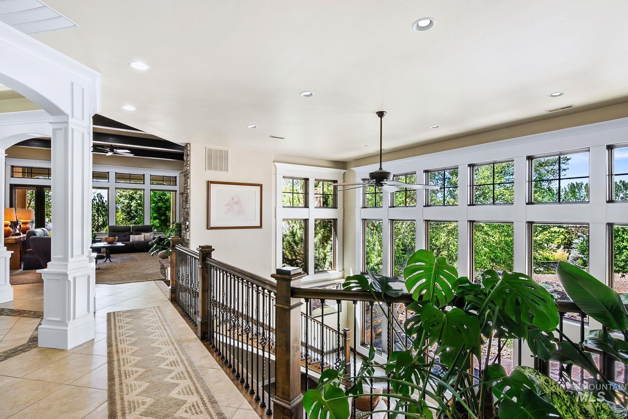 Light-filled upper landing with soaring windows, open railing detail, and picturesque views overlooking the surrounding landscape