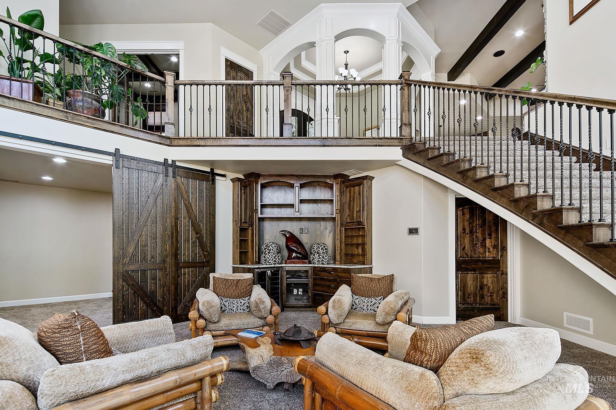 Expansive lower-level gathering space with soaring ceilings, custom built-ins, and sliding barn doors opening to a dedicated theater room?perfect for entertaining, movie nights, or game day hosting
