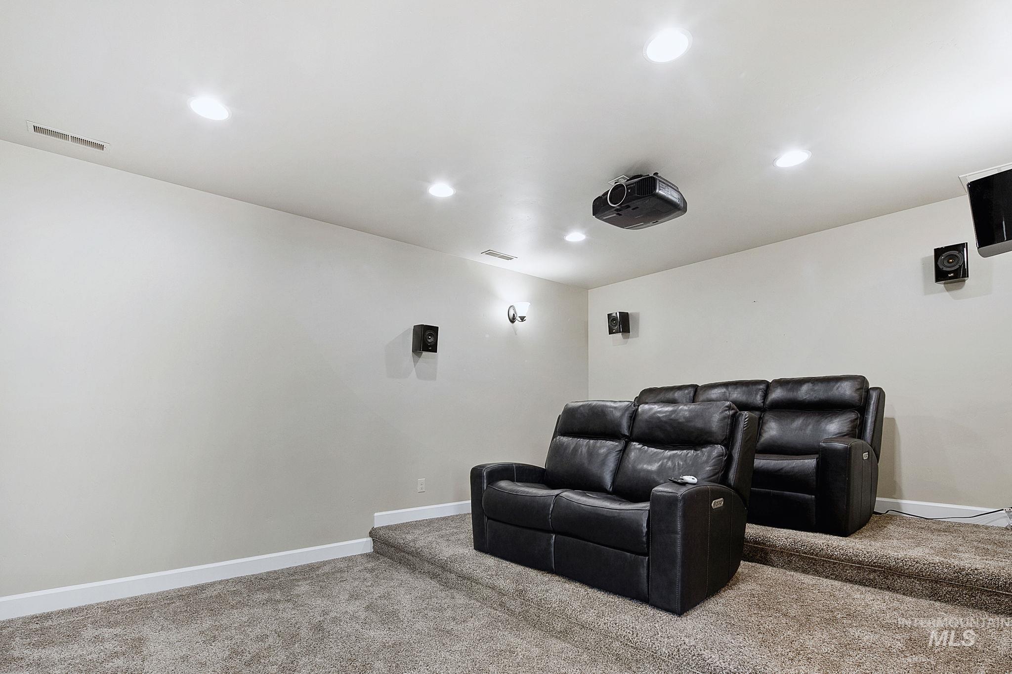 Private theater room complete with an 84-inch screen, surround sound system, and tiered seating platform for an immersive at-home movie experience