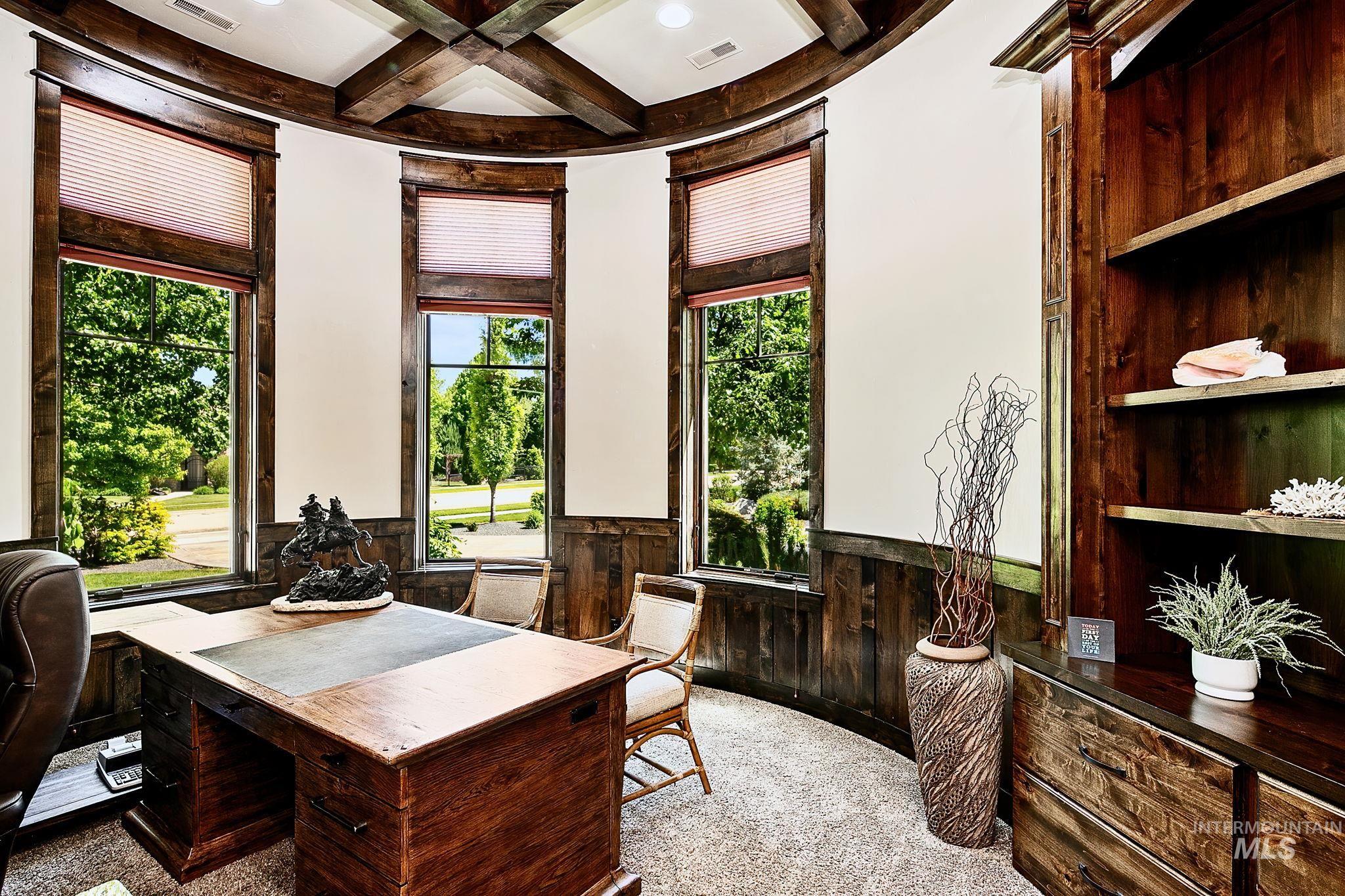 Richly appointed office featuring custom woodwork, dramatic beam ceiling details, and expansive windows with natural light