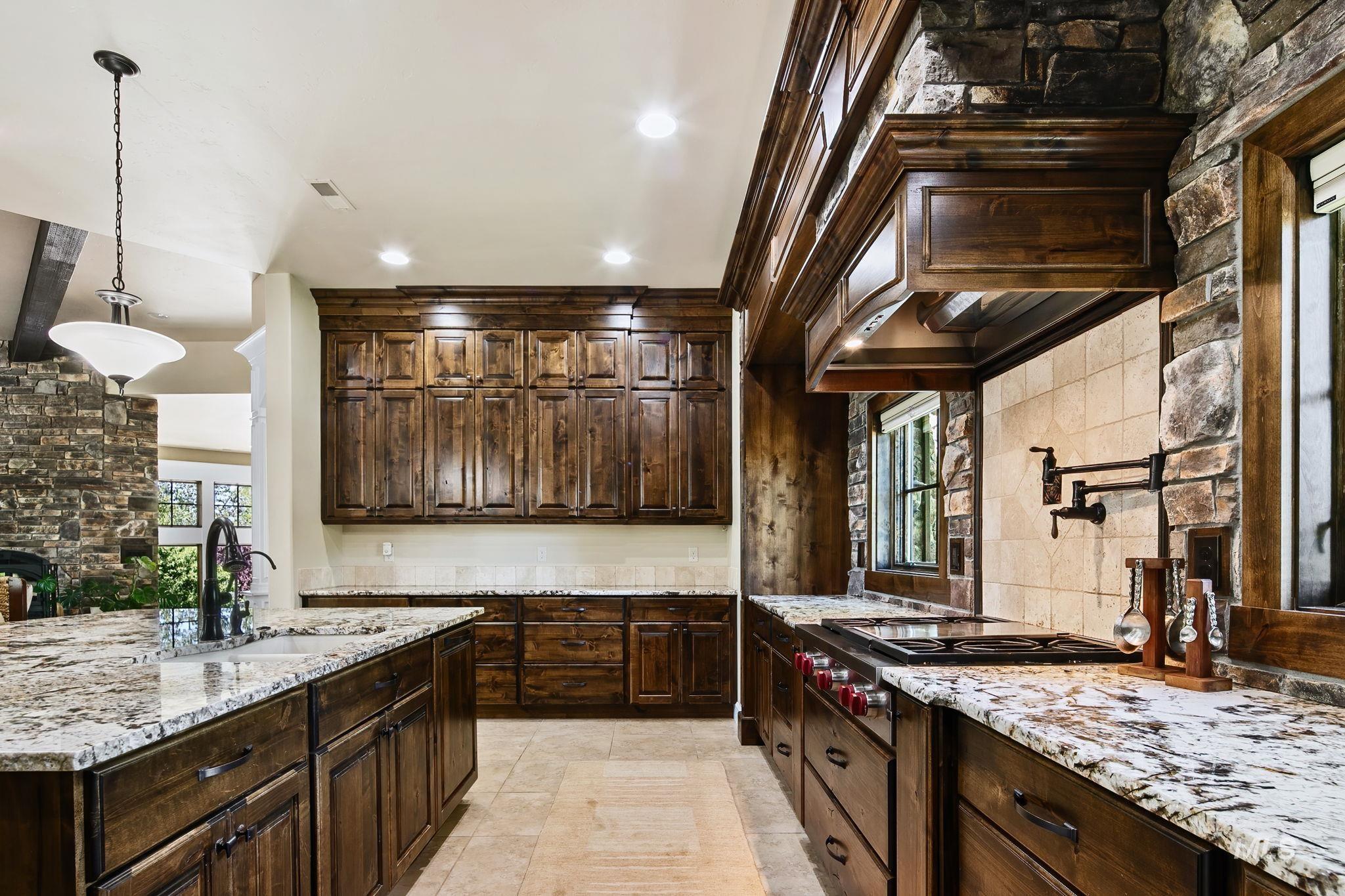 Luxury kitchen showcasing high-end appliances, floor-to-ceiling cabinetry, and an impressive stone surround range alcove