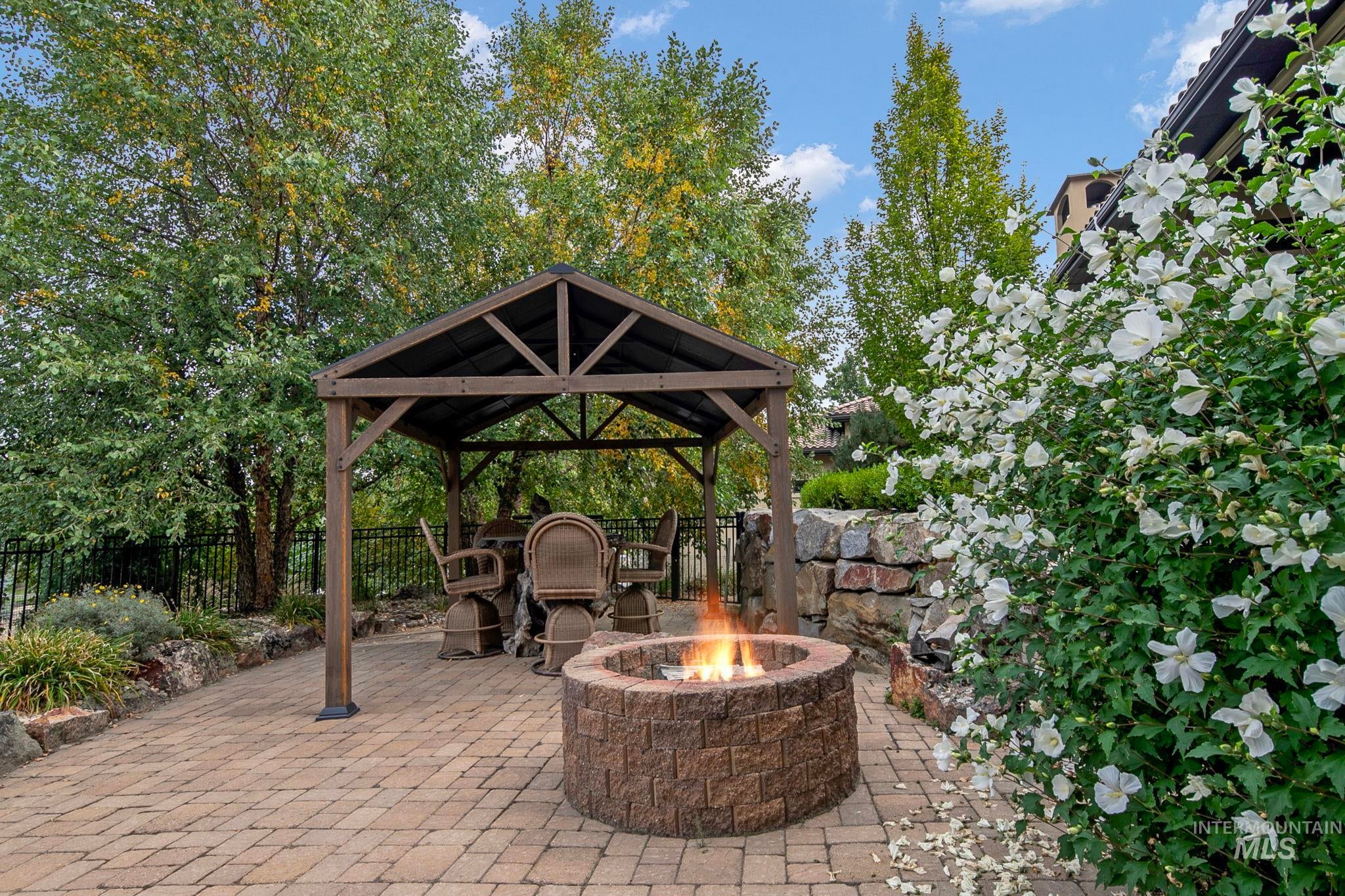 Charming gazebo patio retreat with paver stone hardscaping, gas fire pit, and mature landscaping?creating the perfect setting for outdoor gatherings and quiet evenings