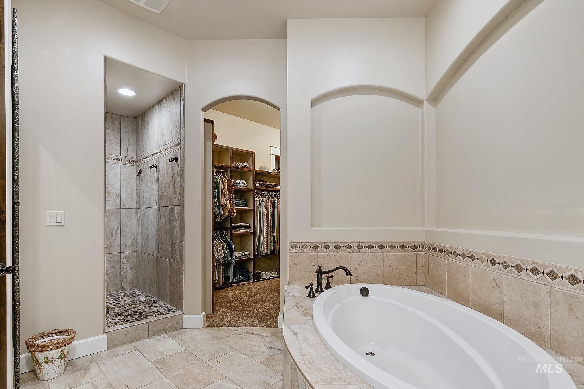 Elegant en suite retreat offering a walk-in shower, oversized soaking tub, and direct access to the spacious walk-in closet