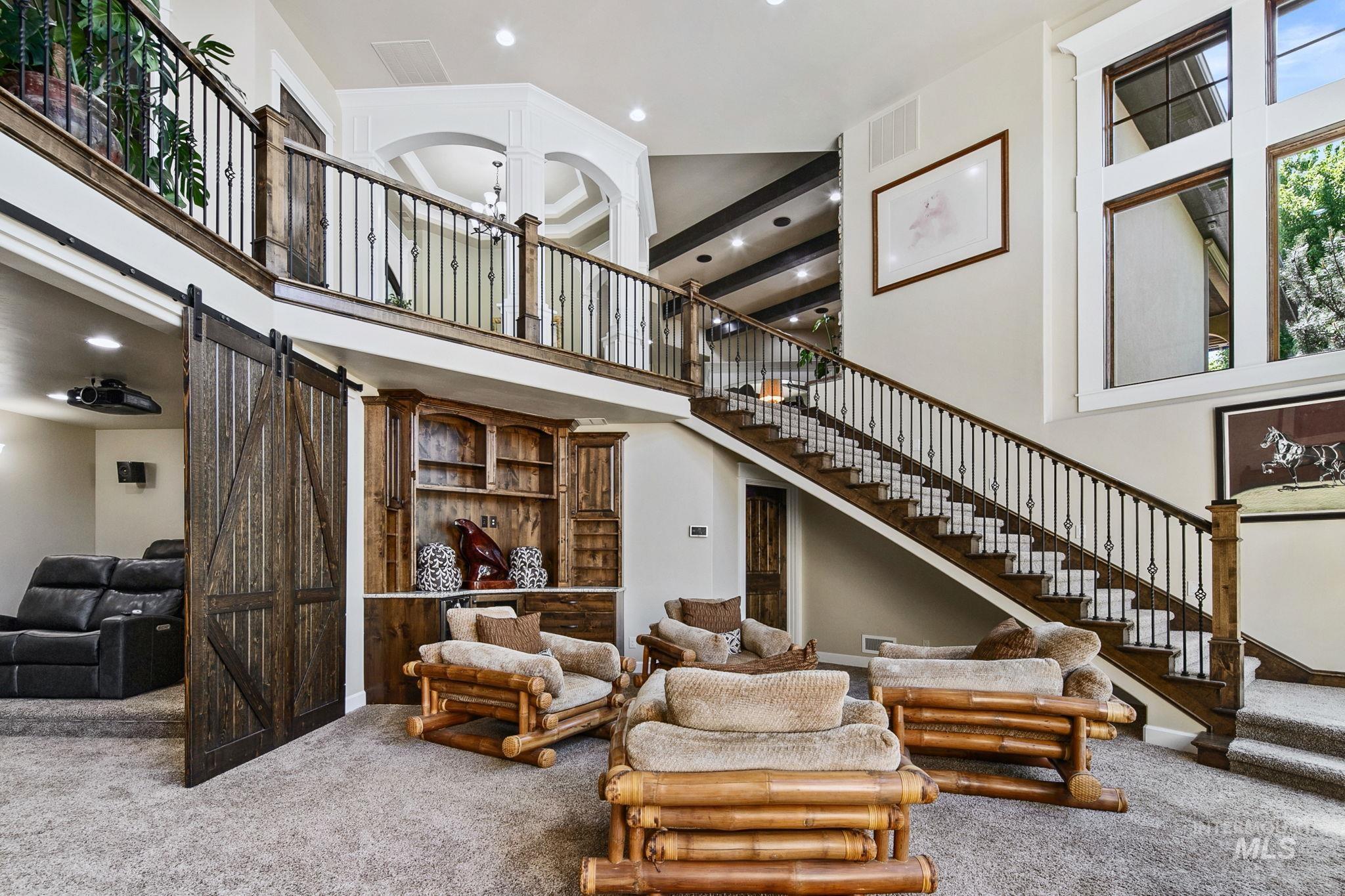 Expansive lower-level gathering space with soaring ceilings, custom built-ins, and sliding barn doors opening to a dedicated theater room?perfect for entertaining, movie nights, or game day hosting