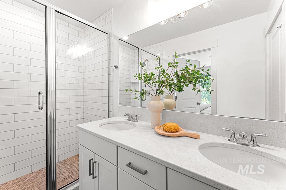 Full bath featuring a stall shower and double vanity