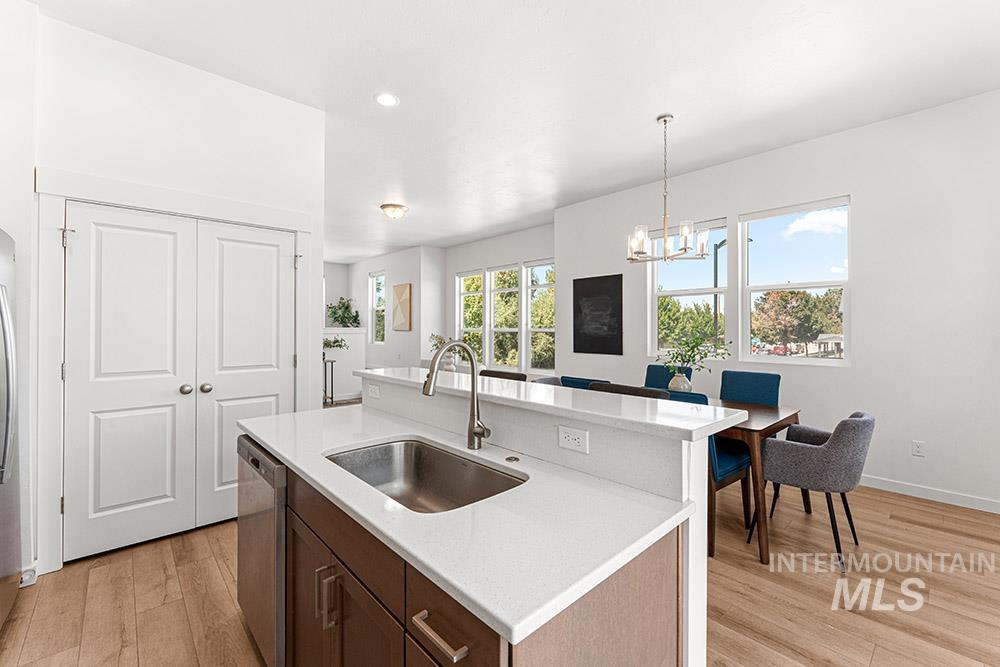 Kitchen with a kitchen island with sink, pendant lighting, light wood-type flooring, dark brown cabinetry, and recessed lighting