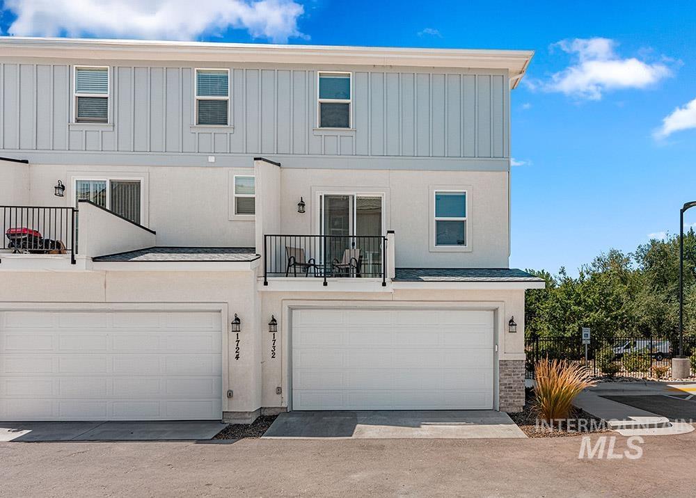 Rear view of house featuring a balcony, a garage, and driveway