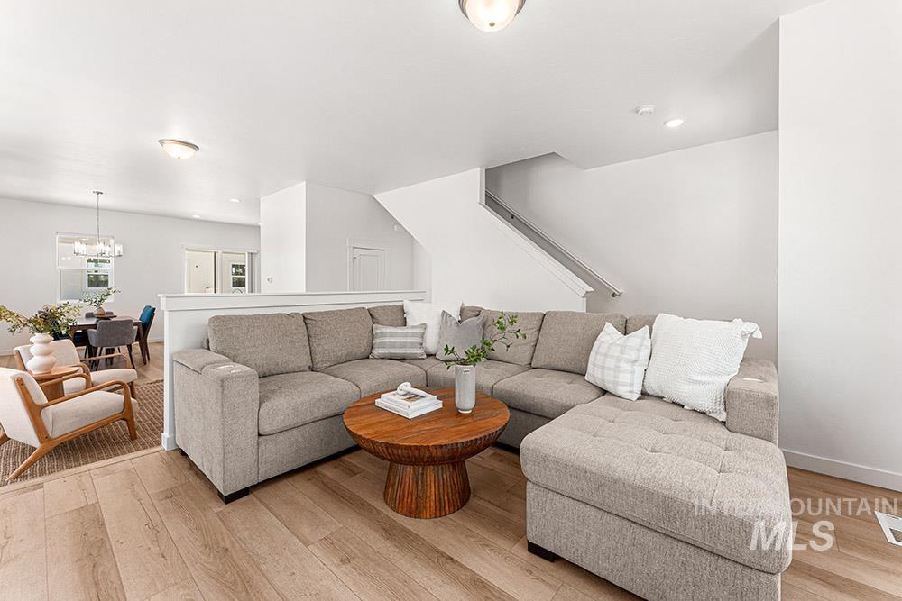 Living area with light wood-style flooring, a chandelier, stairway, and recessed lighting