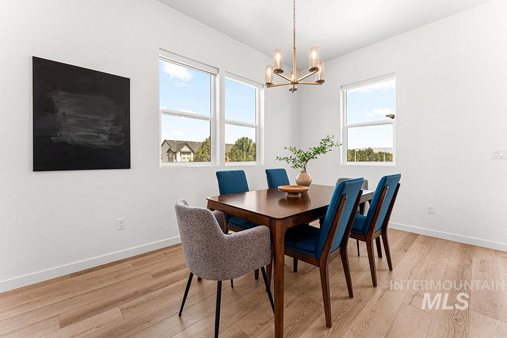 Dining room featuring light wood finished floors, healthy amount of natural light, and a chandelier