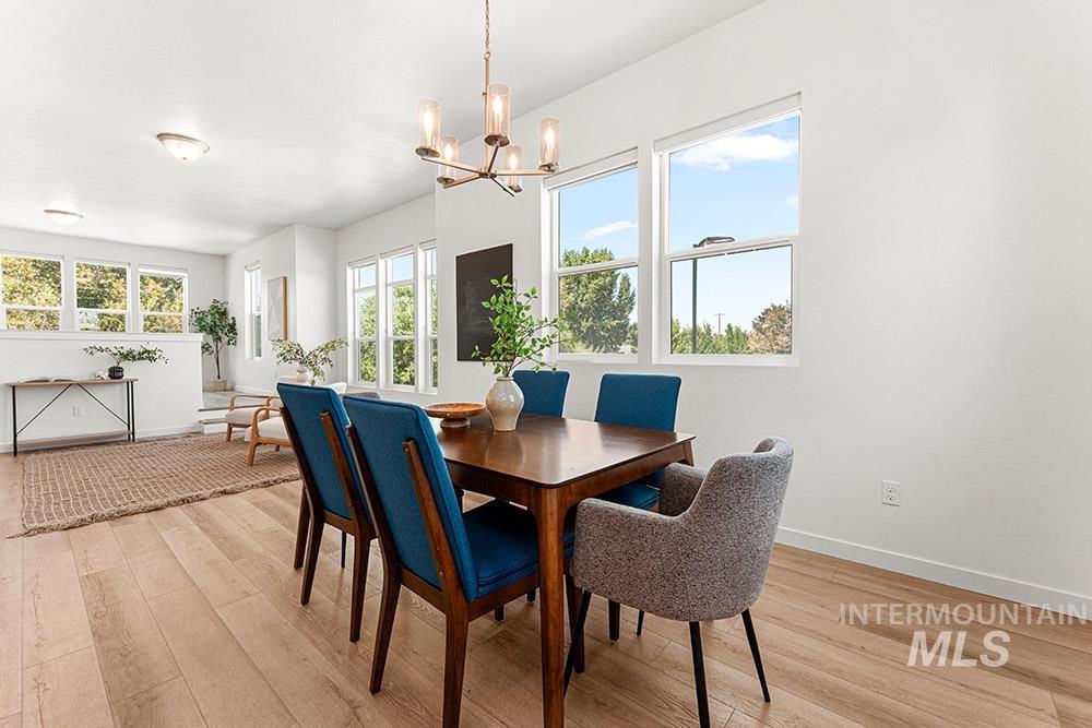Dining space with light wood-style floors, plenty of natural light, and a chandelier