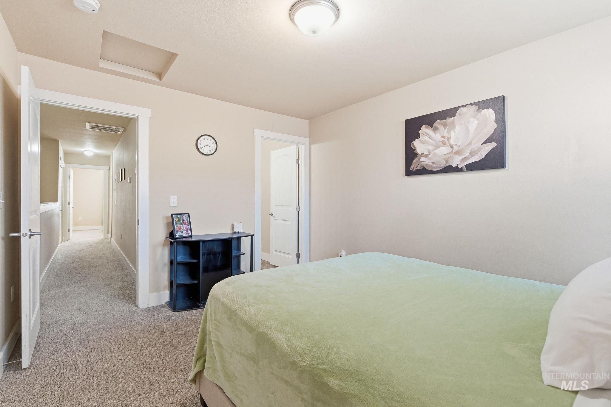 Bedroom featuring attic access and light carpet