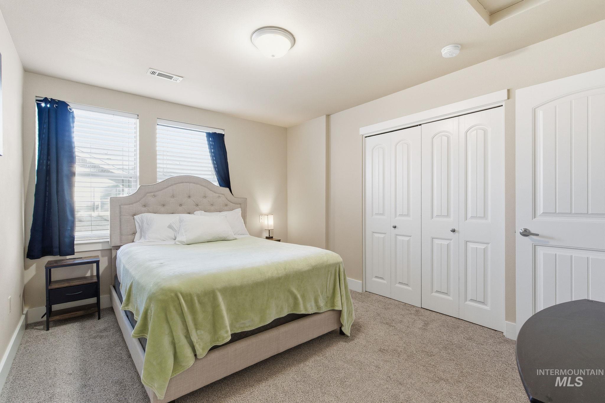 Bedroom with light colored carpet and a closet