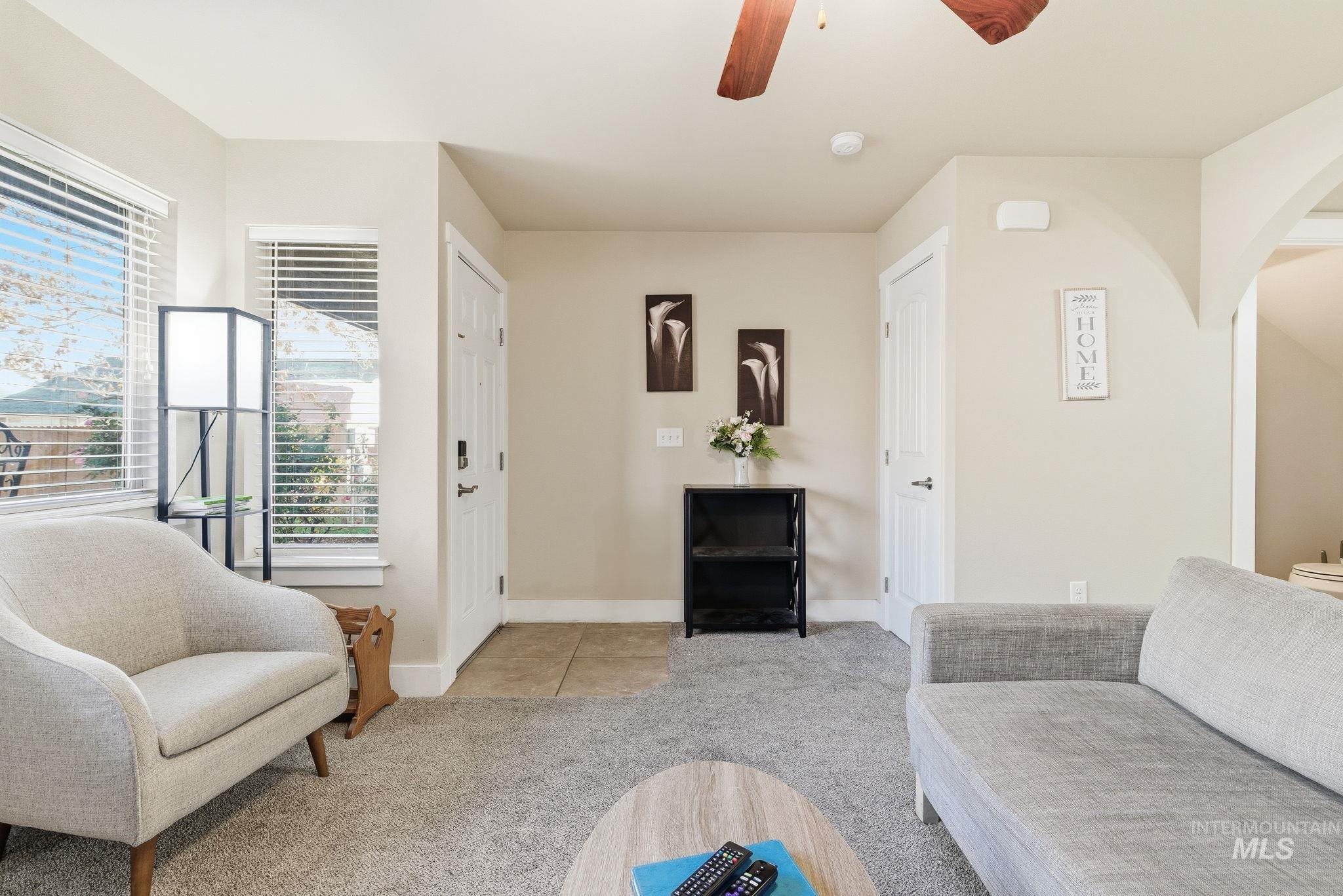 Living area featuring light colored carpet, a ceiling fan, and arched walkways