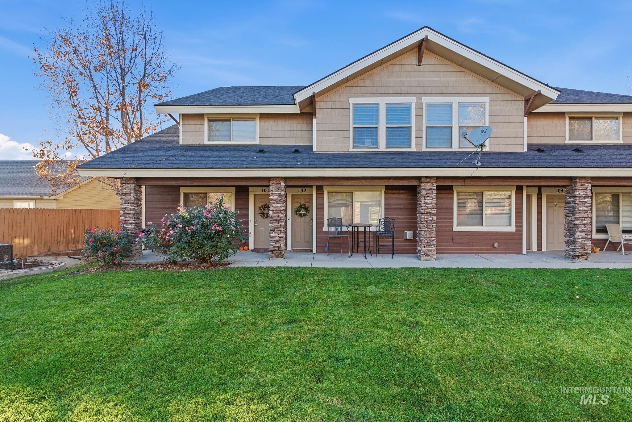 View of front of home with a shingled roof, a patio, and stone siding