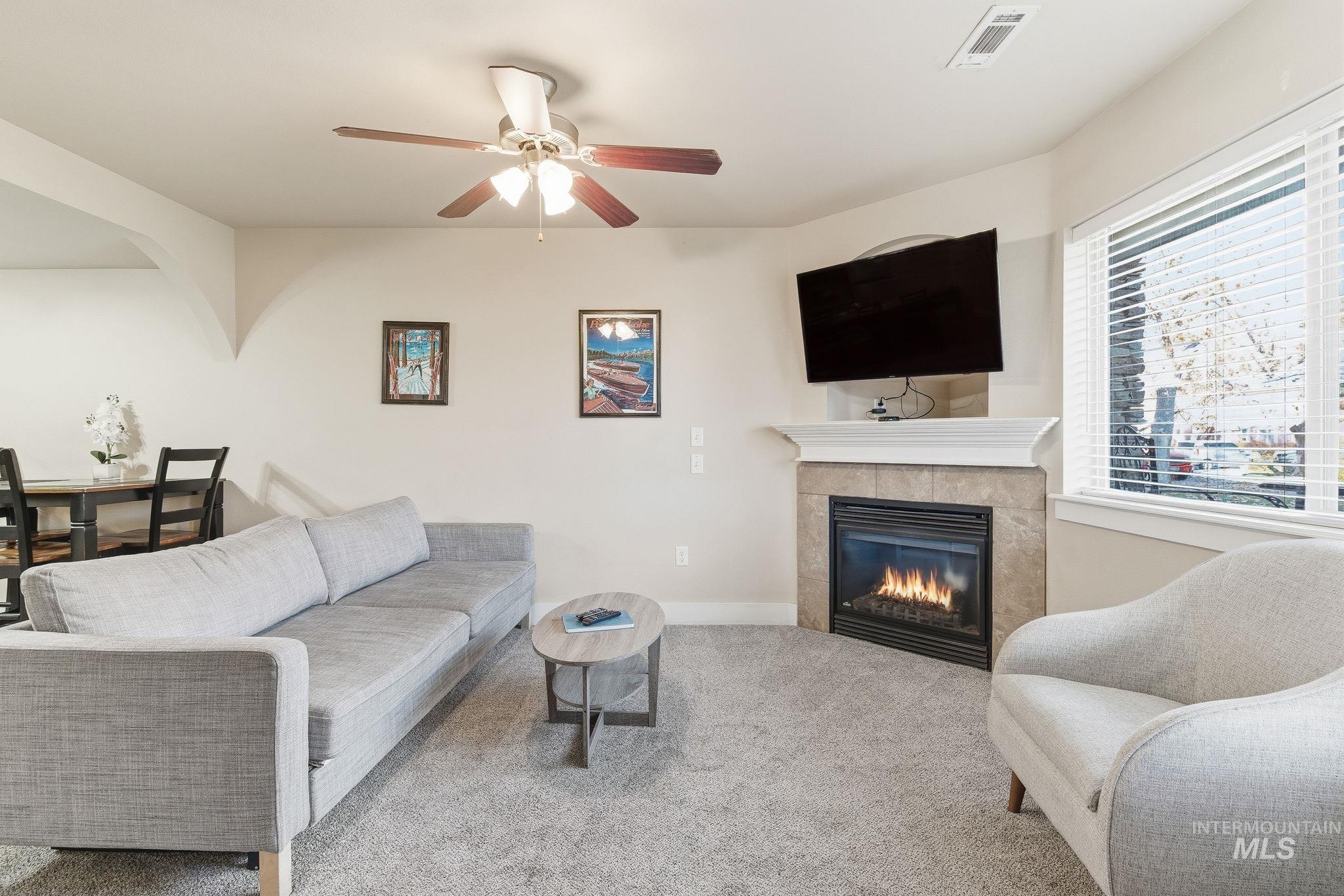 Living area with carpet flooring, a fireplace, and ceiling fan