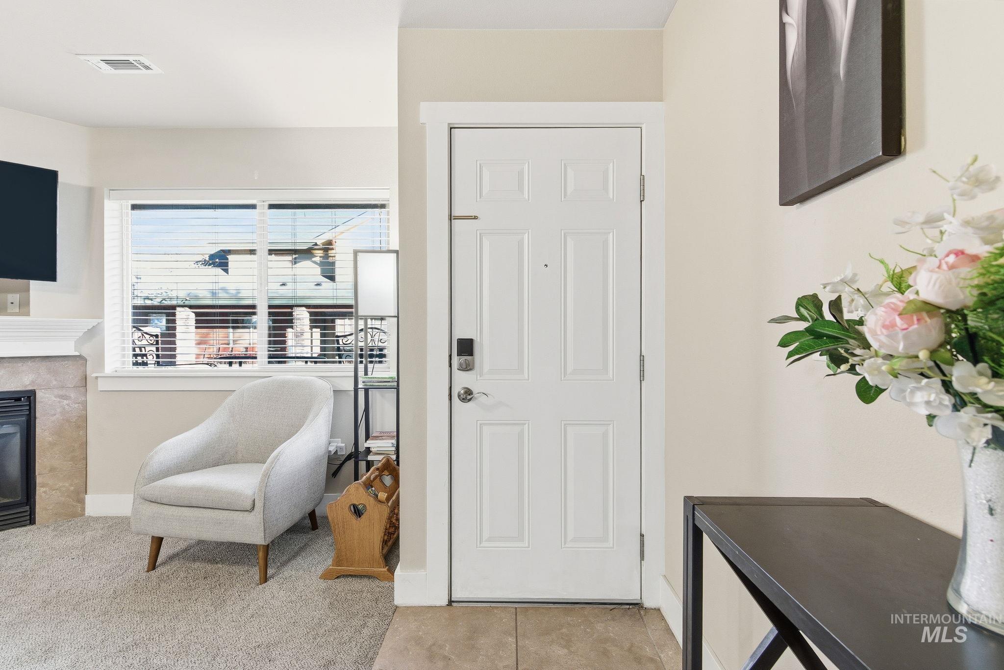 Tiled foyer entrance featuring a premium fireplace and carpet