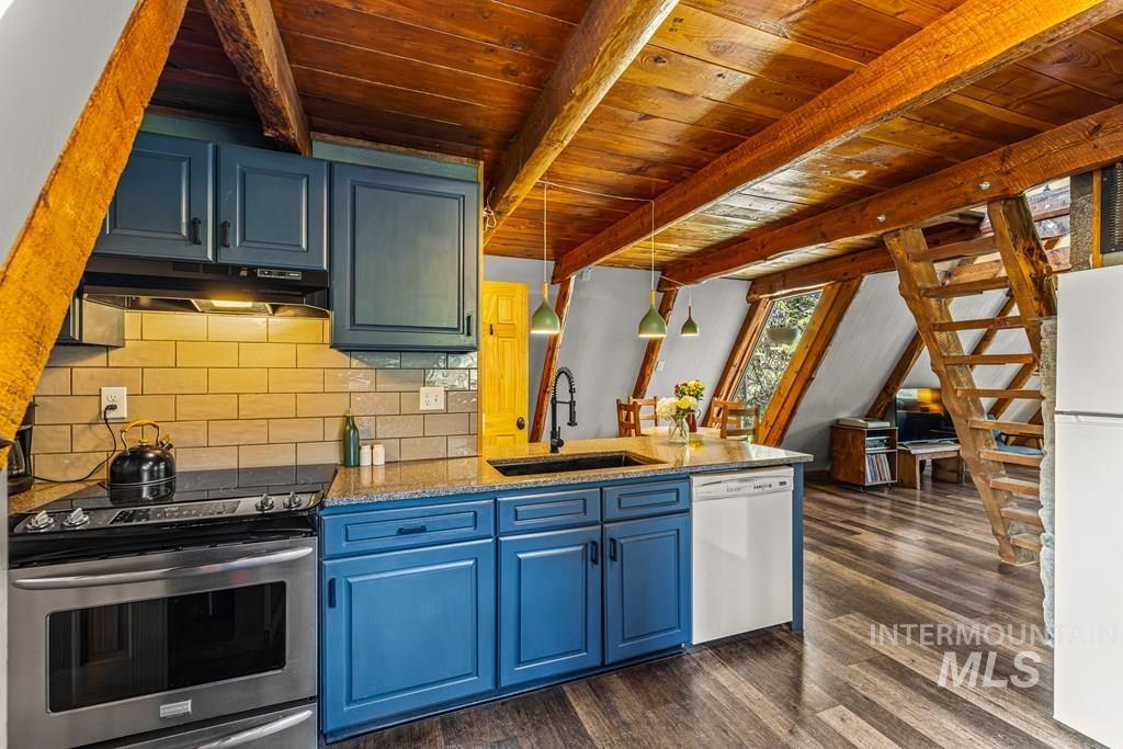 Kitchen featuring pendant lighting, white appliances, blue cabinetry, light stone countertops, and decorative backsplash