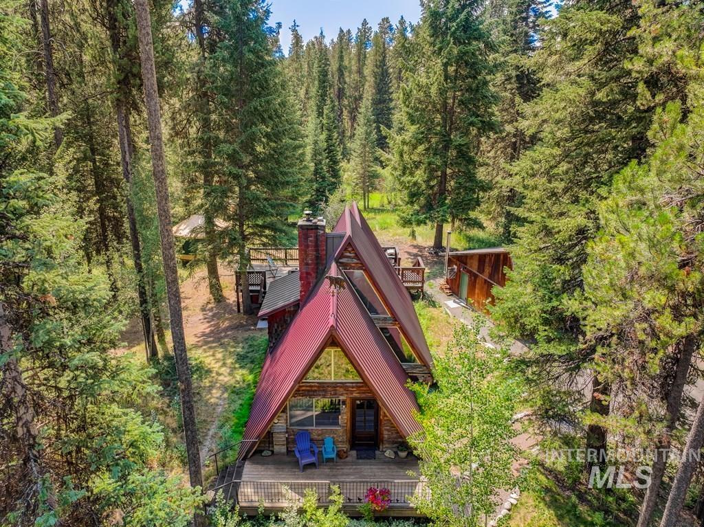 Rear view of property with a chimney, a deck, and a view of trees