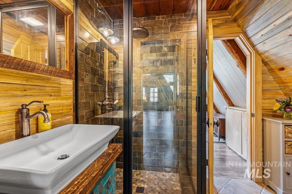 Full bathroom with wood walls, a shower stall, vanity, and wooden ceiling