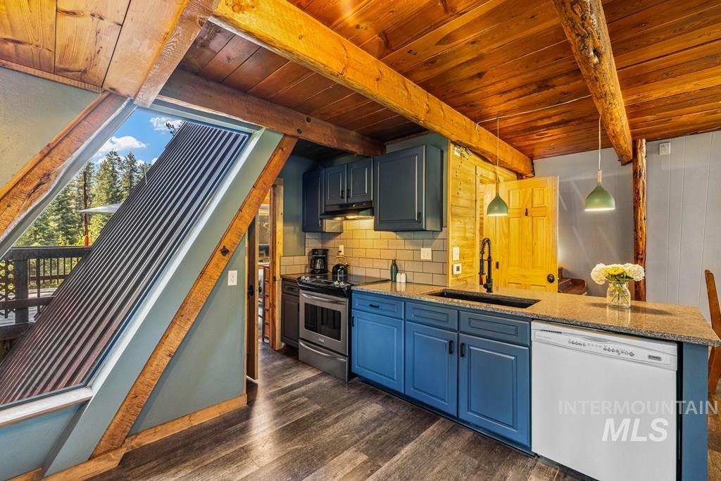 Kitchen with light stone counters, pendant lighting, dishwasher, stainless steel range with electric cooktop, and dark wood-style flooring