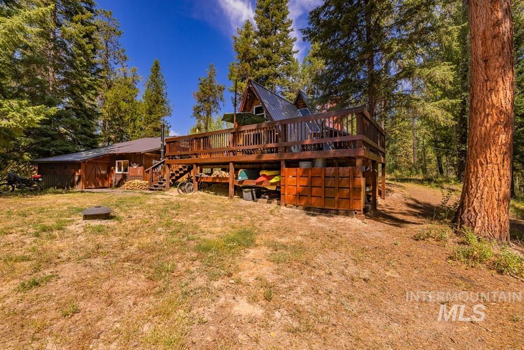 Rear view of property with a wooden deck, stairs, a lawn, and a metal roof