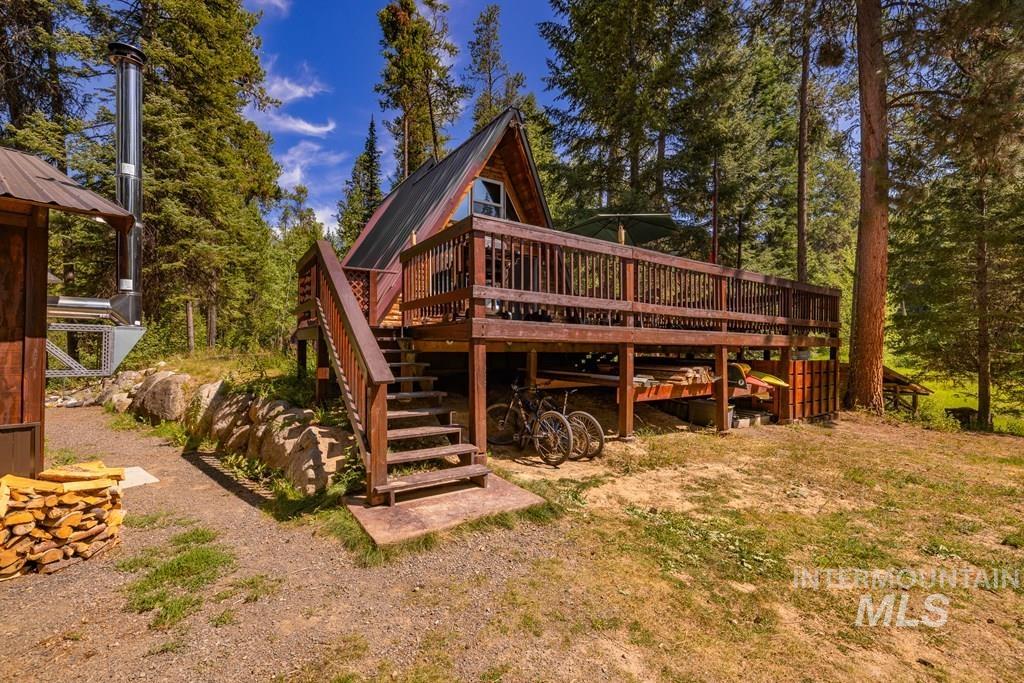 Back of property with stairs, a wooden deck, and a metal roof