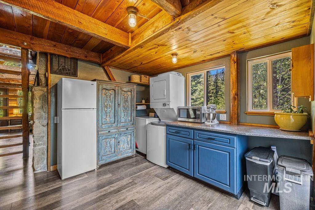 Kitchen with blue cabinetry, freestanding refrigerator, open shelves, a wooden ceiling with exposed beams, and dark wood-type flooring