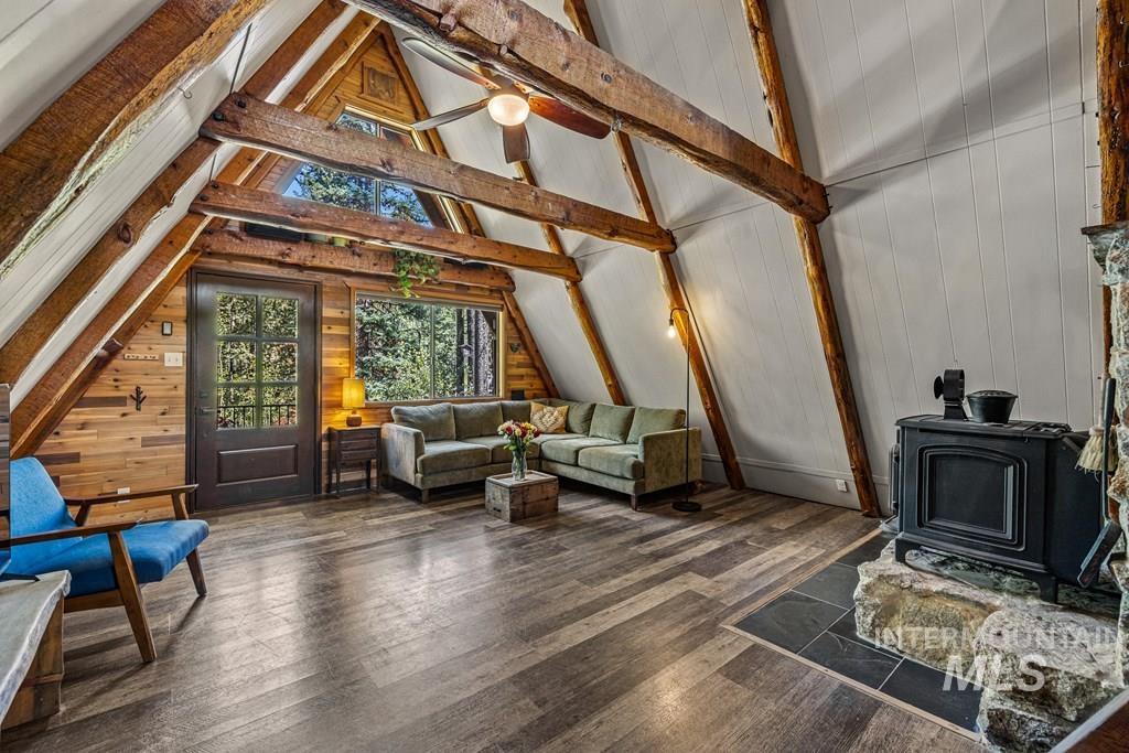 Living area featuring a wood stove, wooden walls, and dark wood finished floors