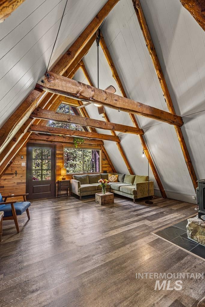 Additional living space featuring a wood stove, dark wood-style flooring, and wood walls