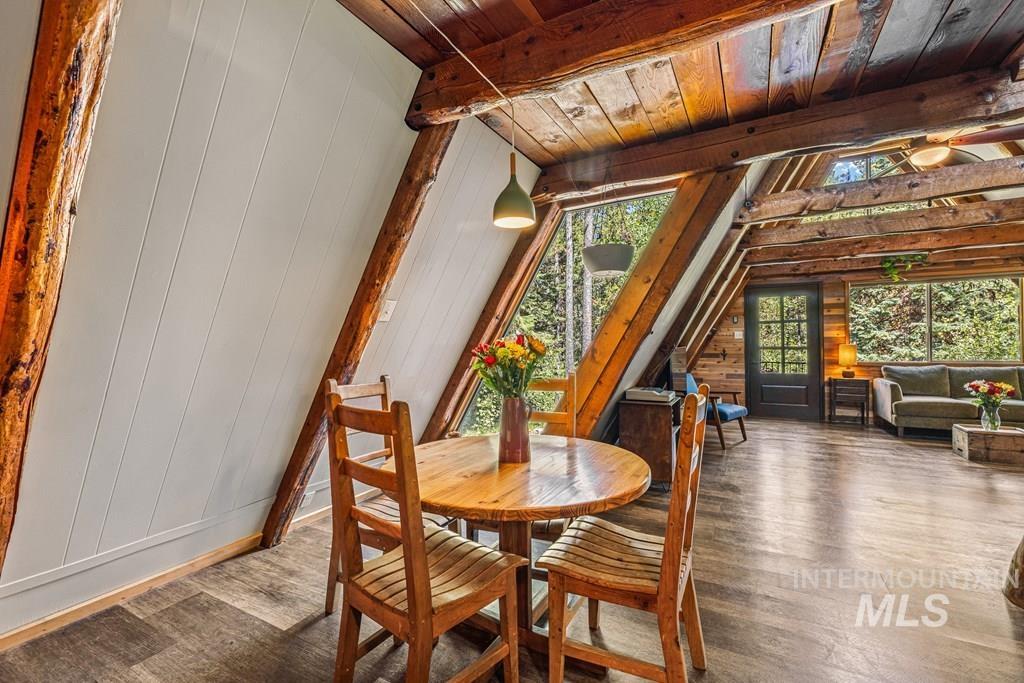 Dining area with hardwood / wood-style flooring, a wooden ceiling with exposed beams, and wood walls
