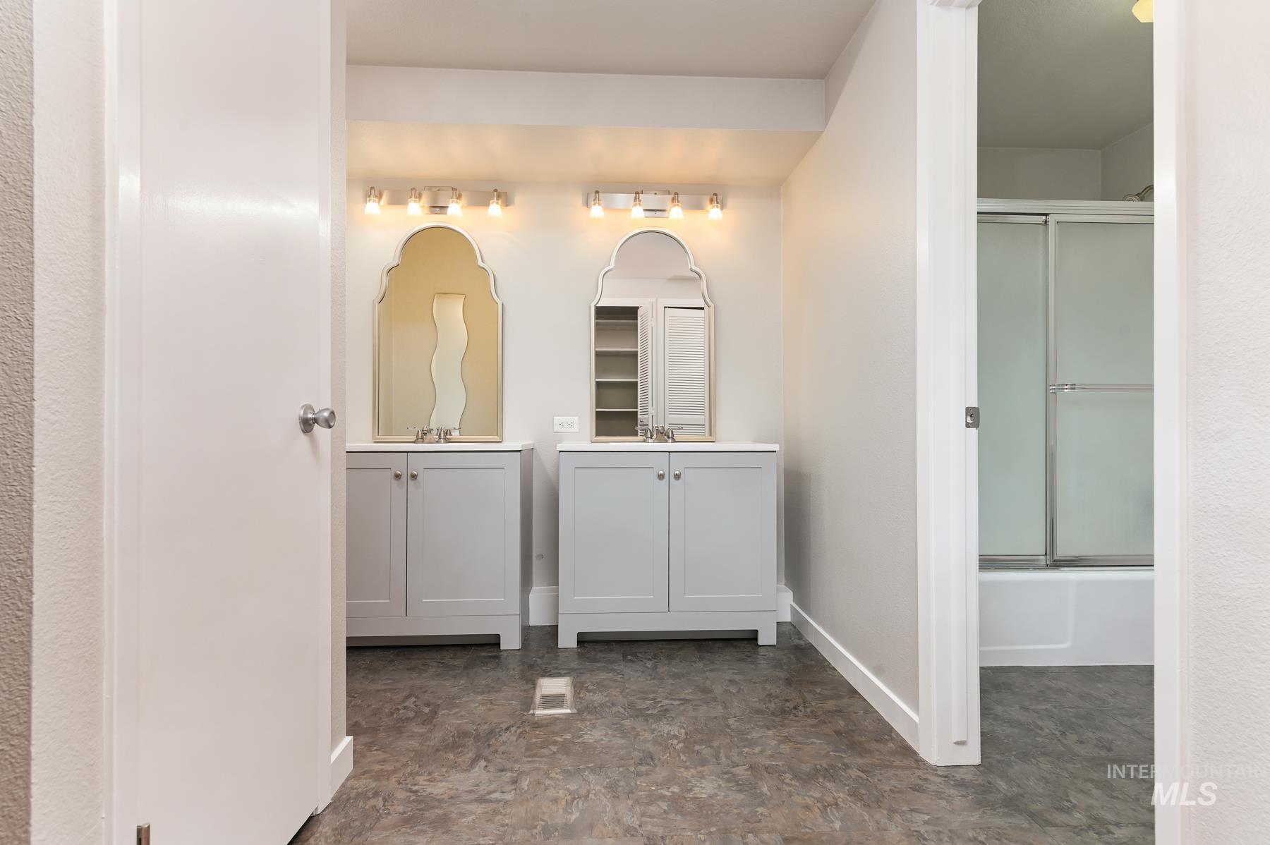 Bathroom with two vanities and combined bath / shower with glass door